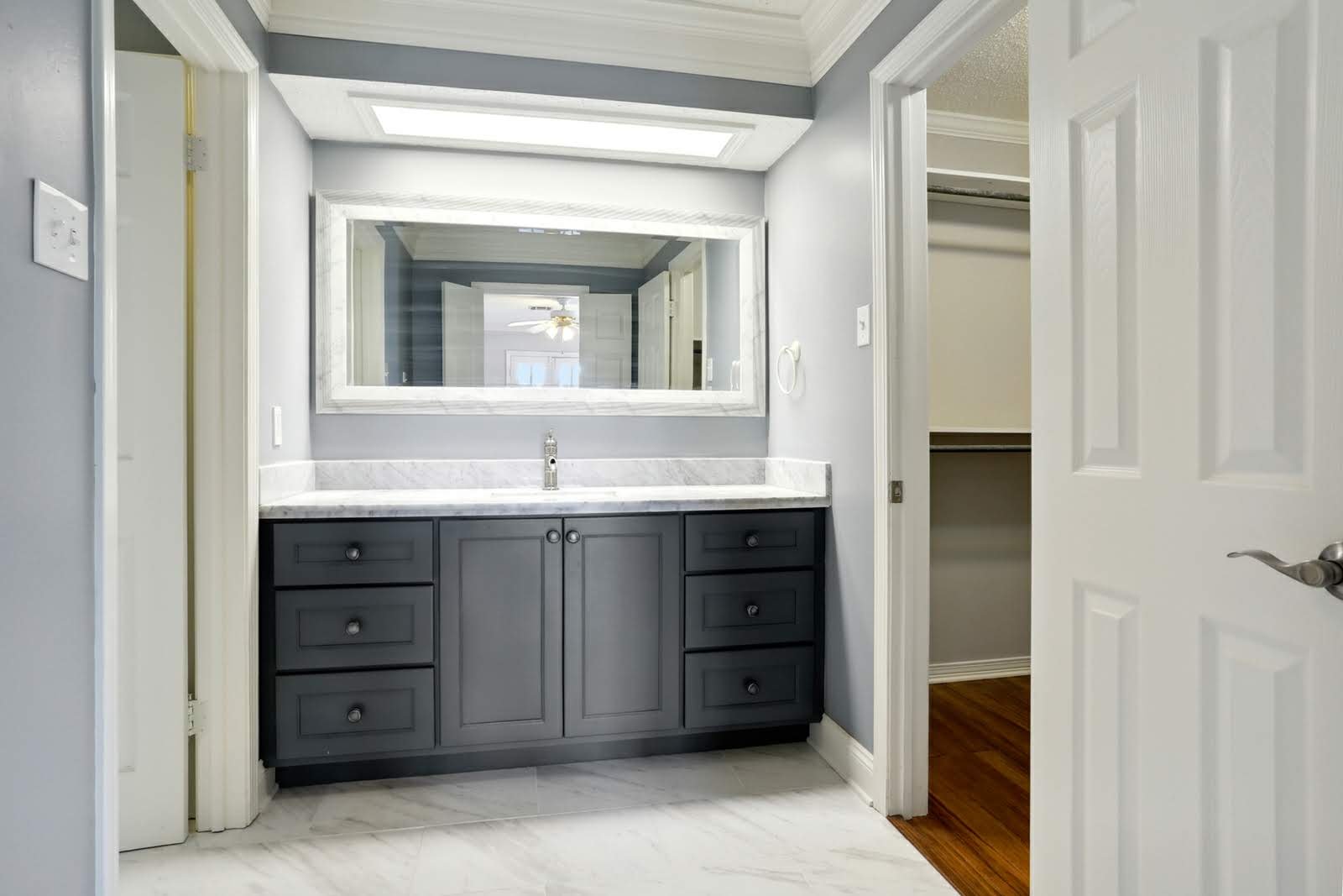 custom dark gray Bathroom vanity with white marble countertop, large mirror, and a sink. 