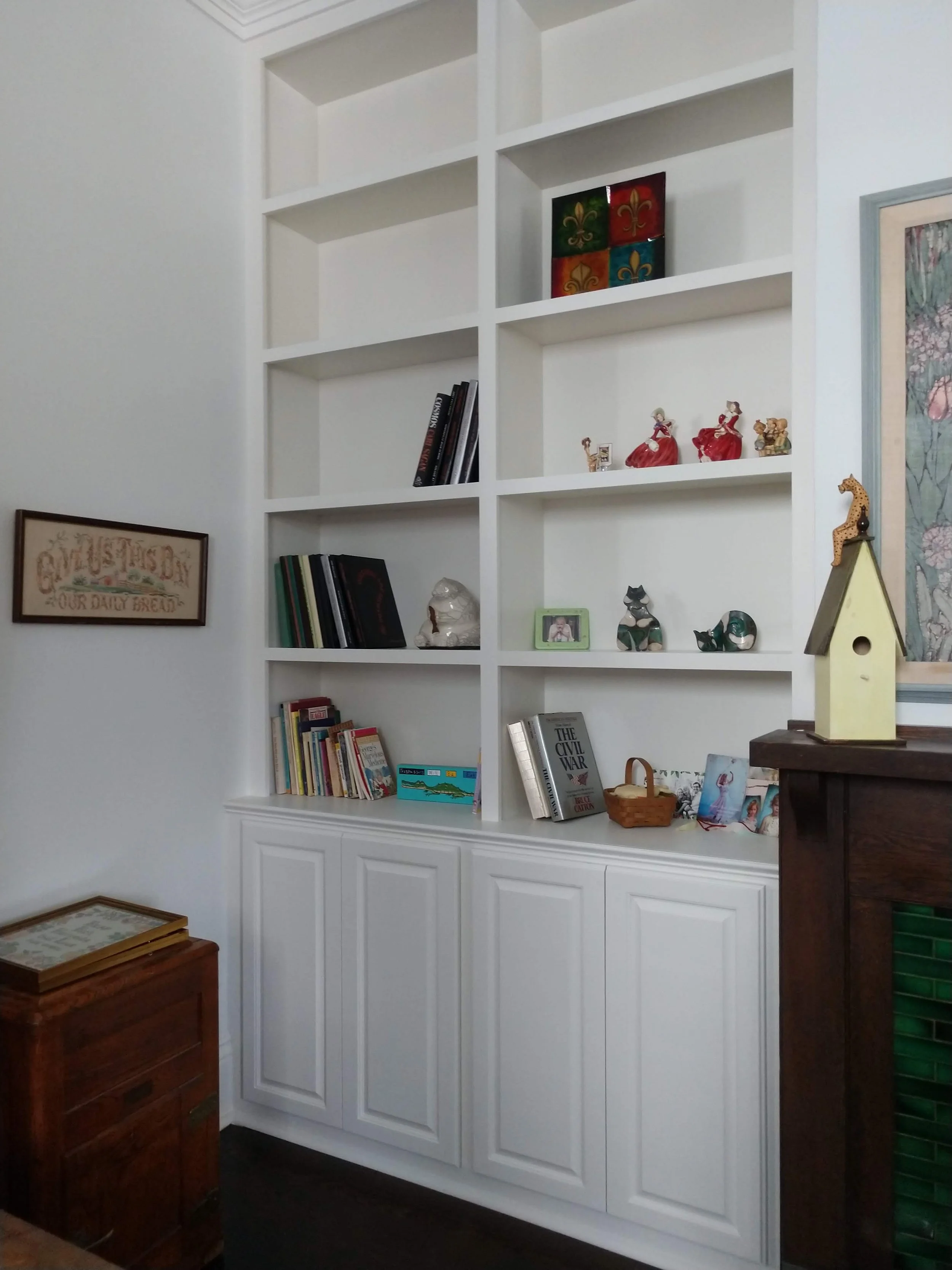 White built-in bookshelf with decorative items, books, and framed photos in a living room.