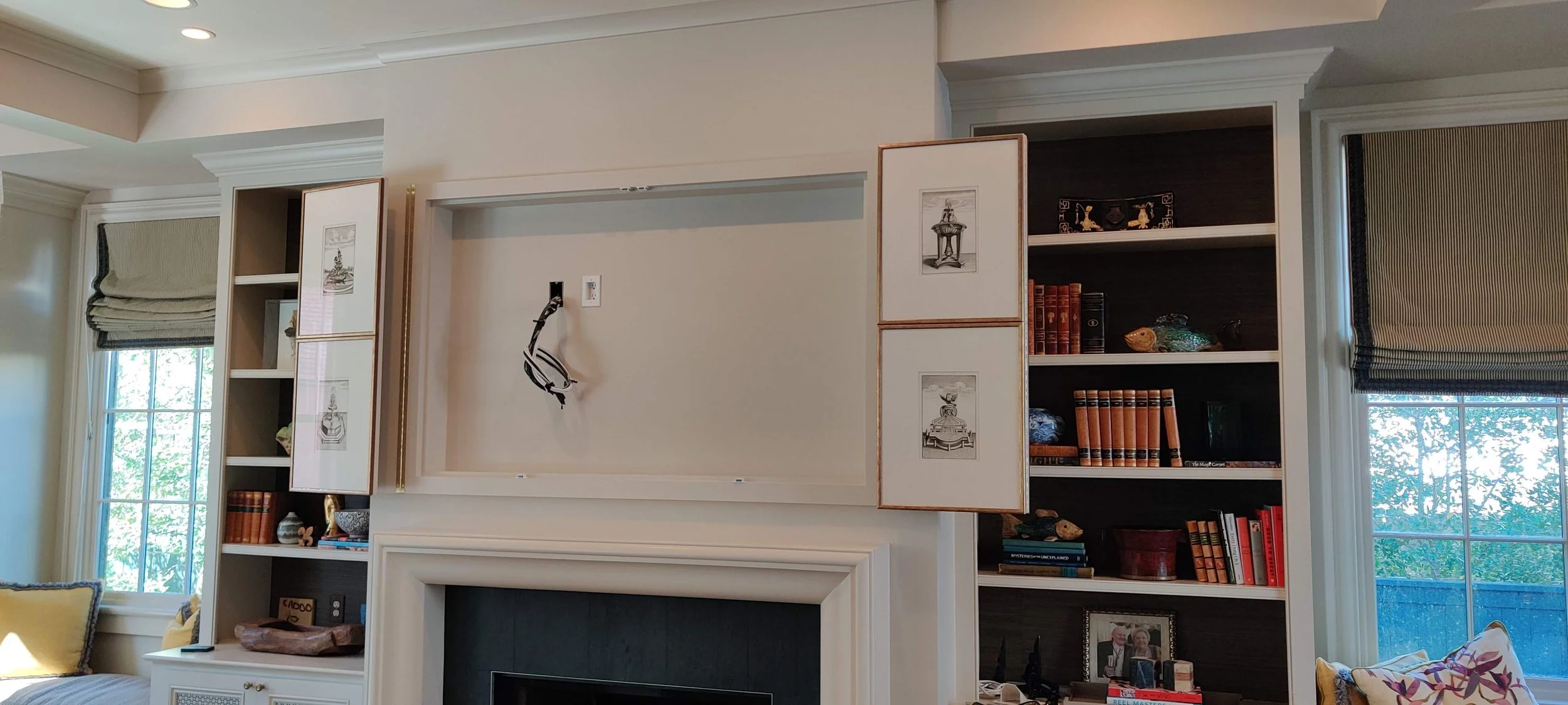 Custom built recess for TV over mantel with folding panels covered in artwork to hide TV when closed.