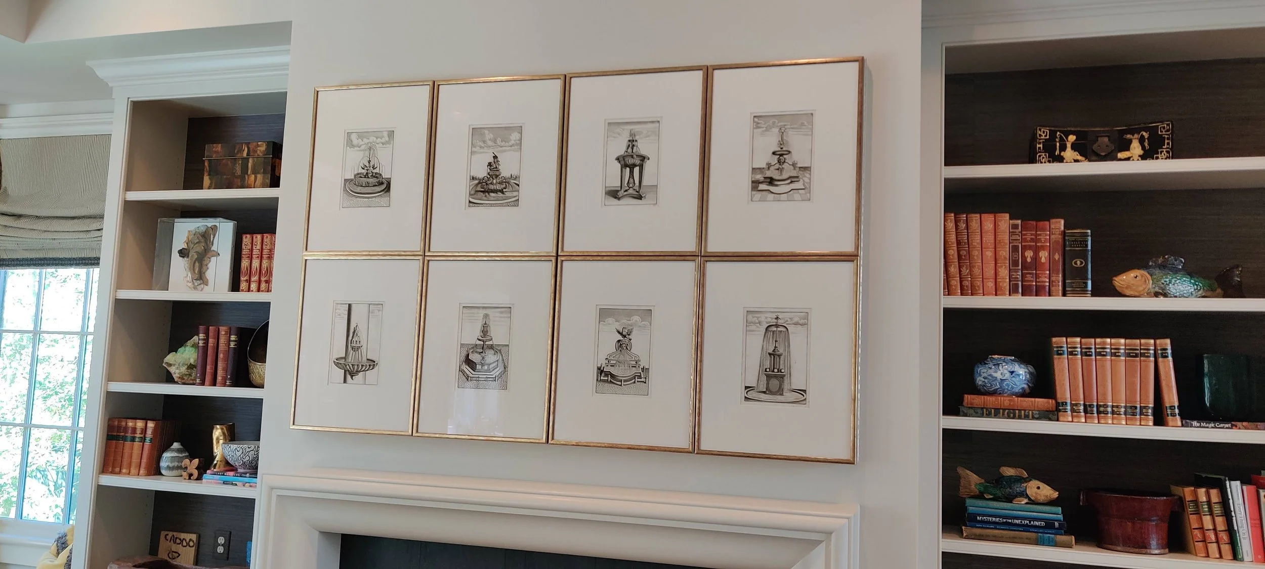 A wall with nine framed black-and-white pictures of fountains arranged in a 3x3 grid.