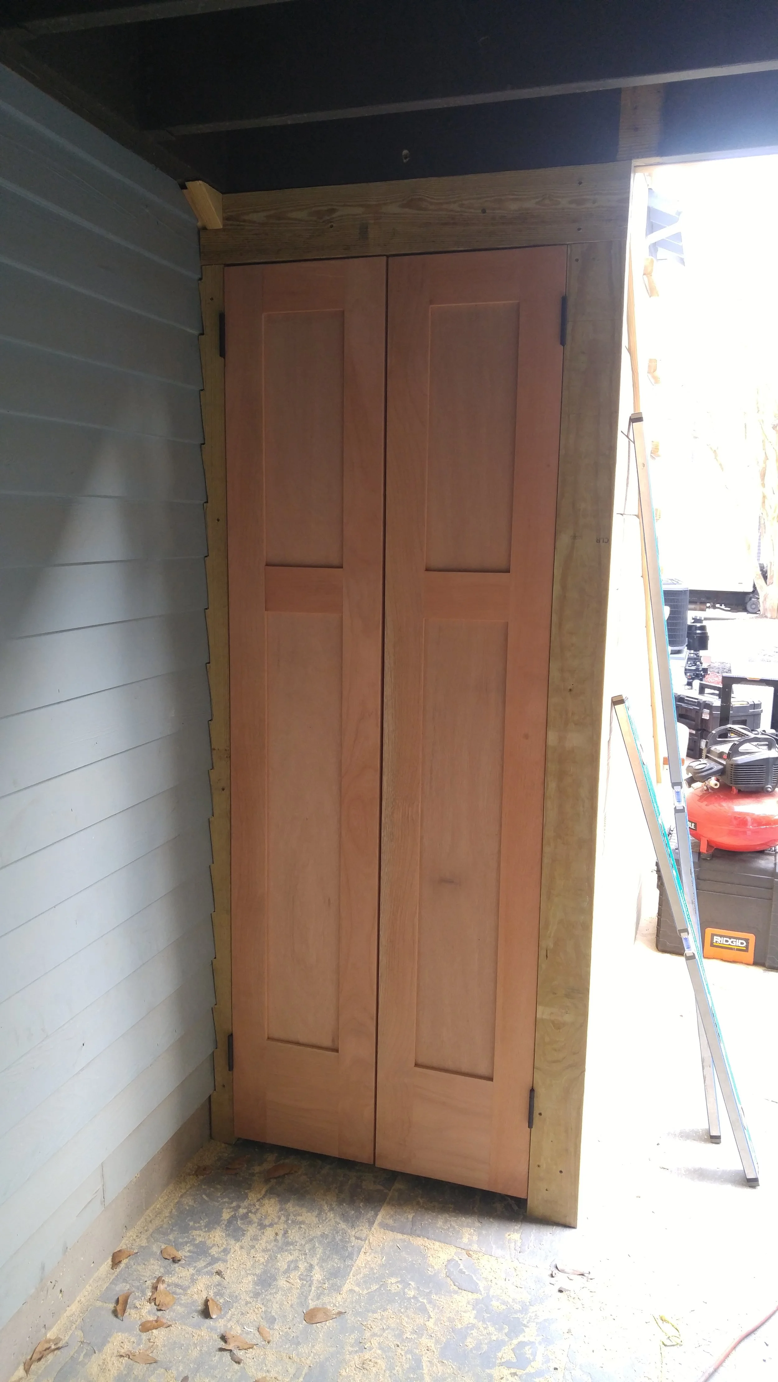 Wooden double doors installed under exterior stair case.