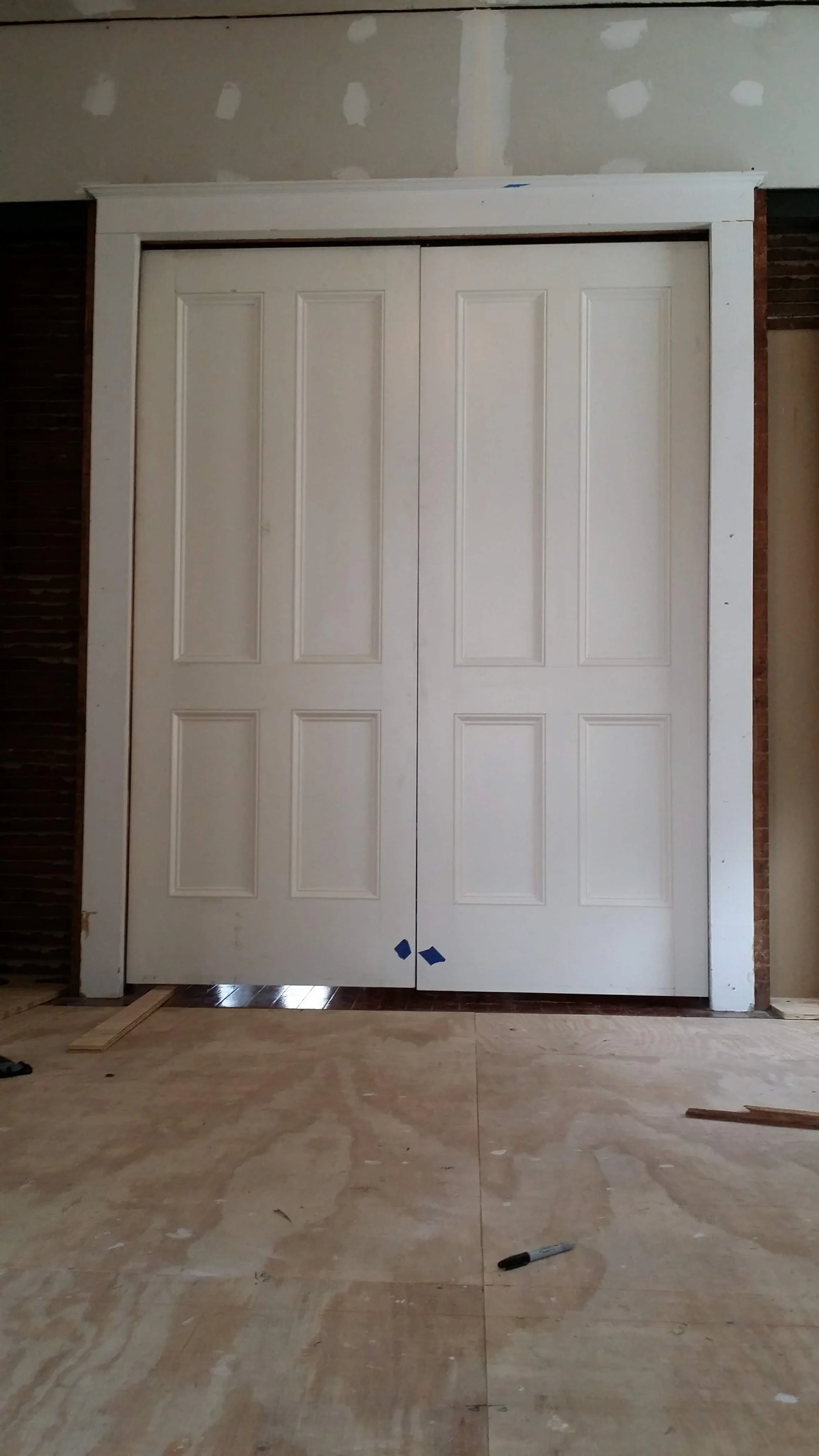 custom Double white pocket doors in a room under construction with unfinished walls and flooring.