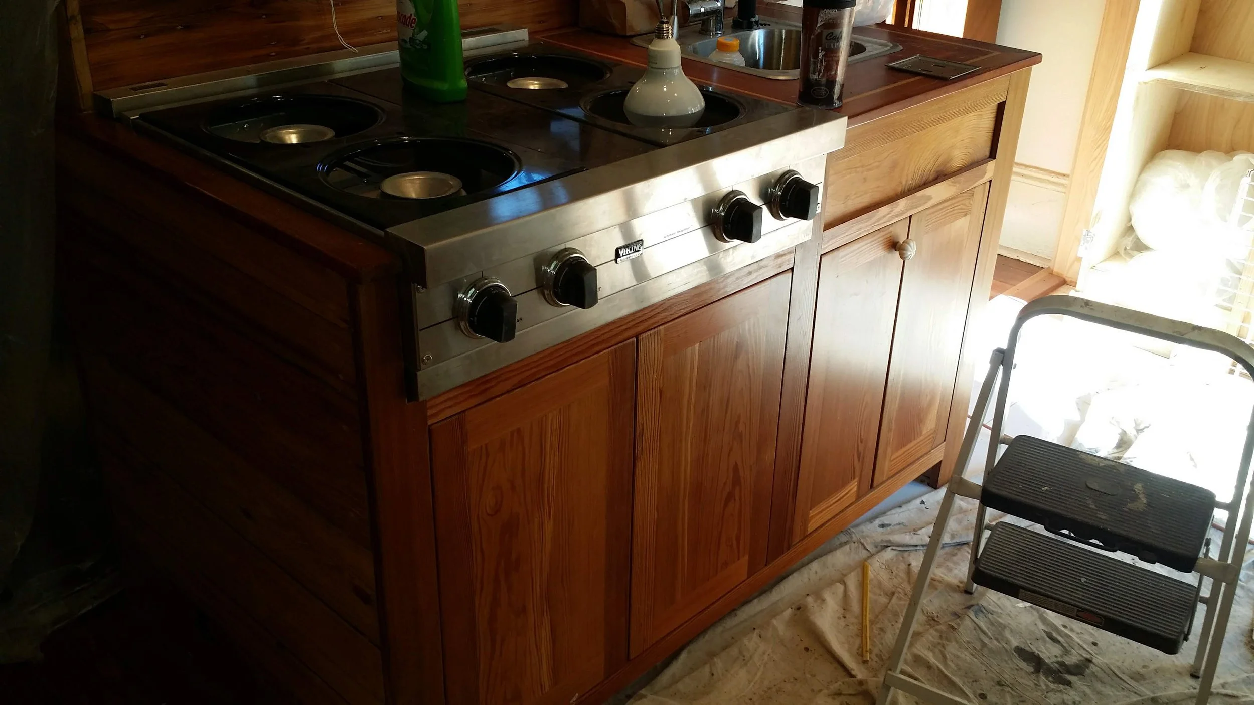 A reclaimed heart pine kitchen cabinet with a stainless steel stove on top