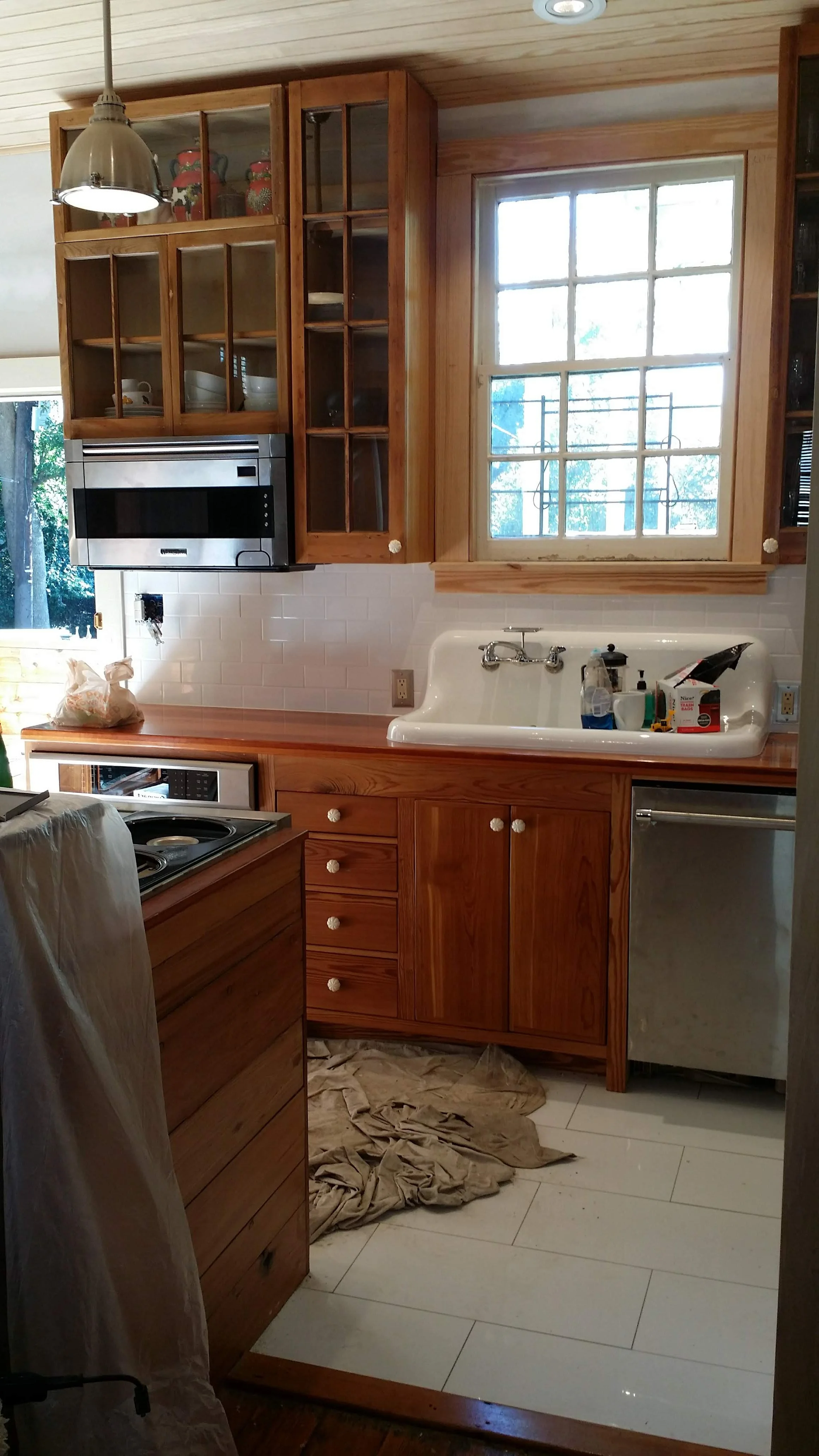 Kitchen with reclaimed heart pine cabinets, a window, a white farmhouse sink 