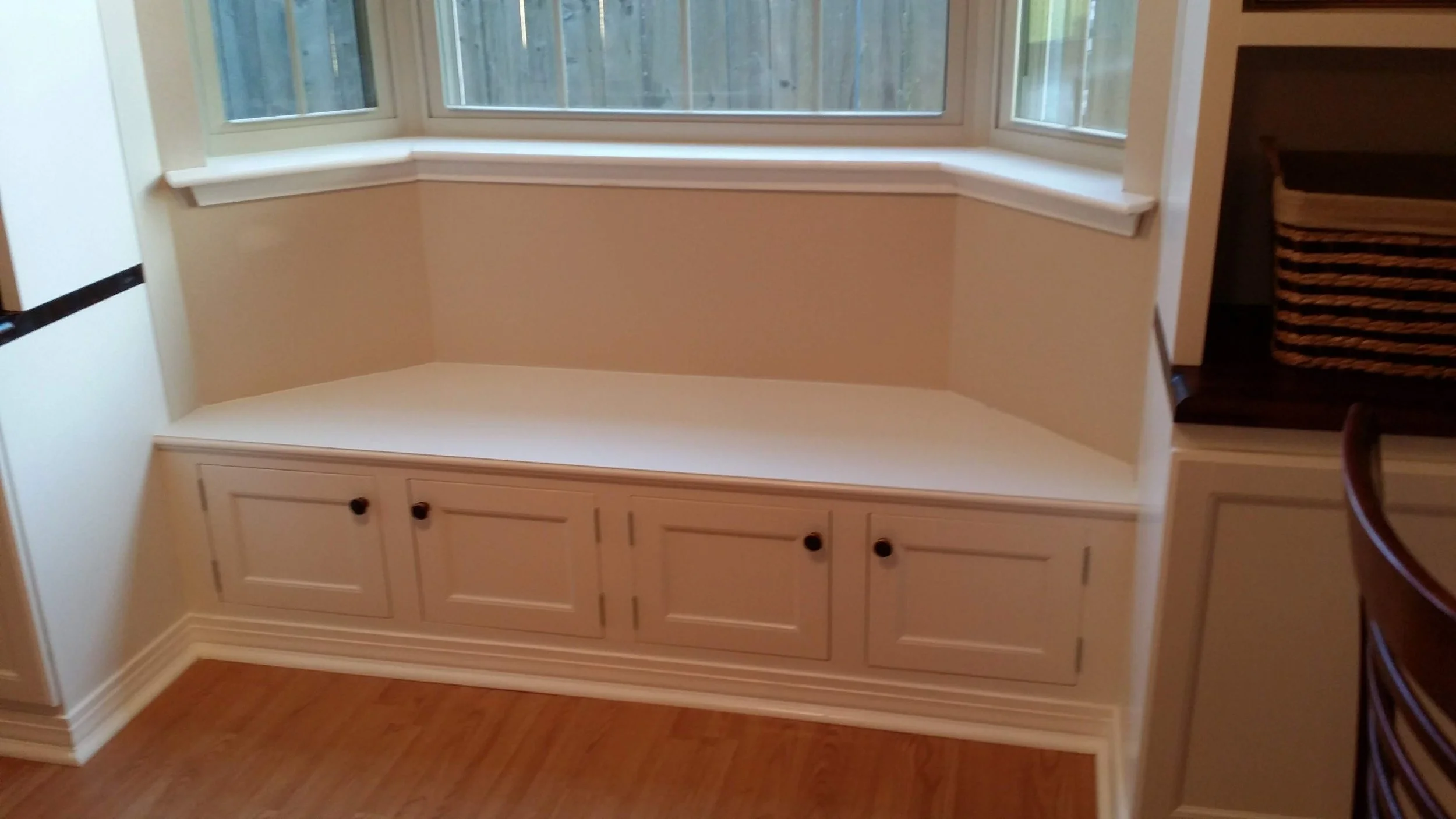 Built-in window seat with cabinet storage underneath in a kitchen or dining area.