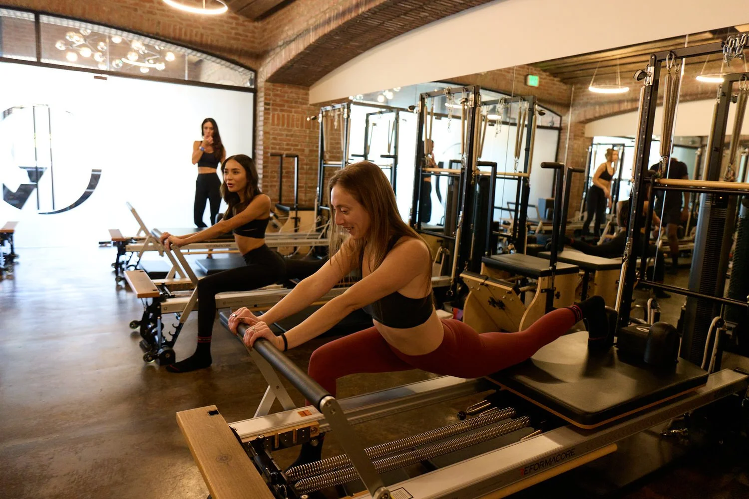 Women exercising on Pilates reformer machines in Reformacore, West LA.