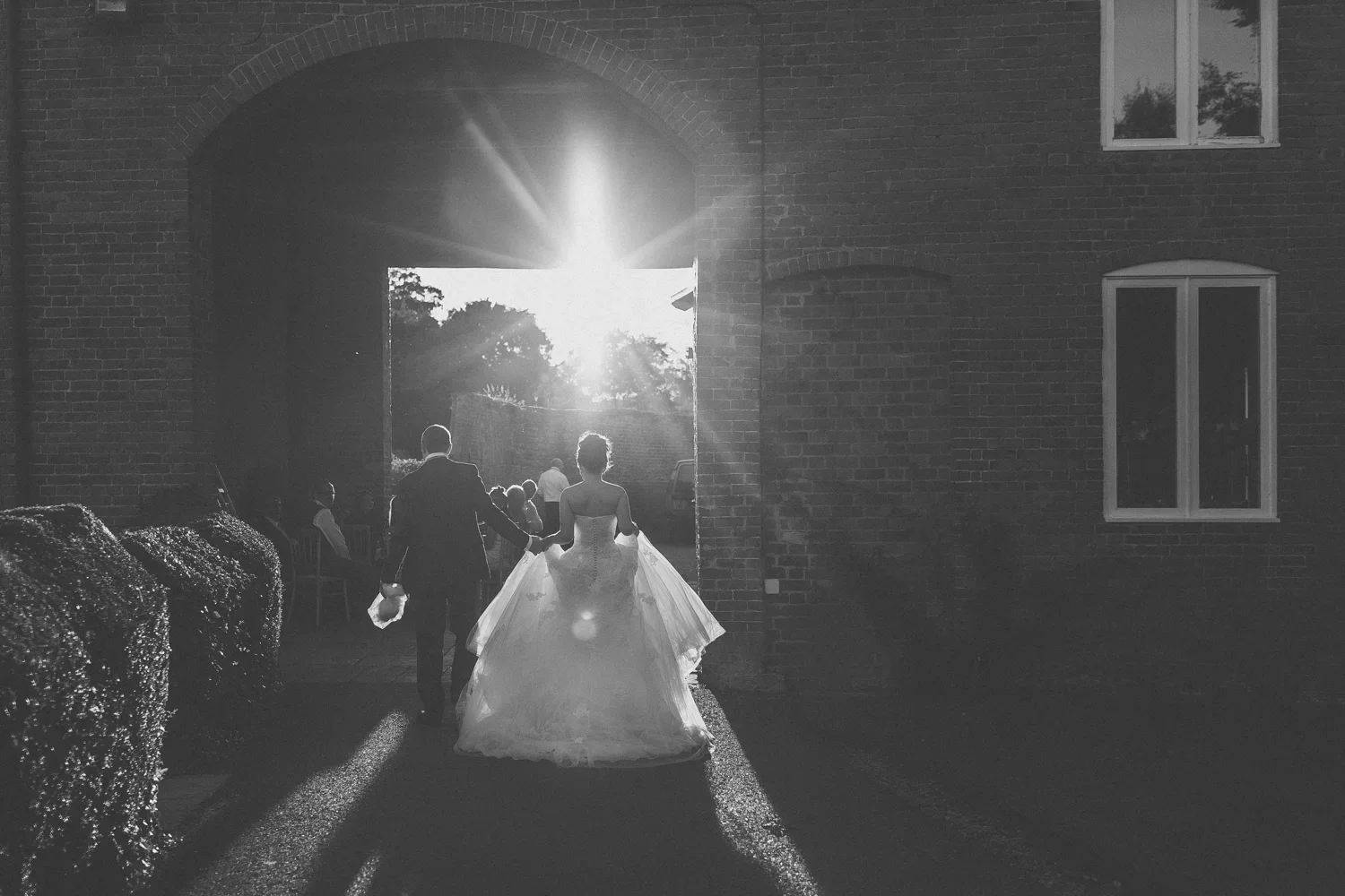 Bride and groom walking out of a building with the sun setting behind them.