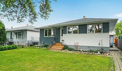 A single-story house with a gray roof, white and gray exterior, front steps, and a well-maintained yard.