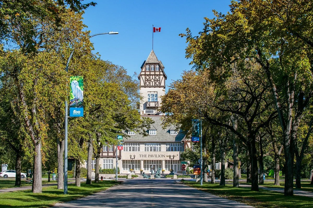 A historic building labeled 'The Pavilion' with a tower, surrounded by green trees and a clear blue sky.