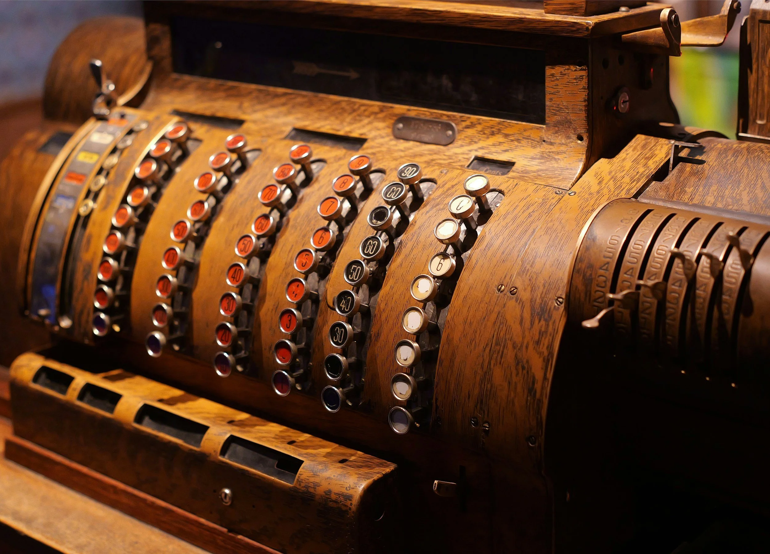 A vintage wooden adding machine with rotating numbered cylinders.