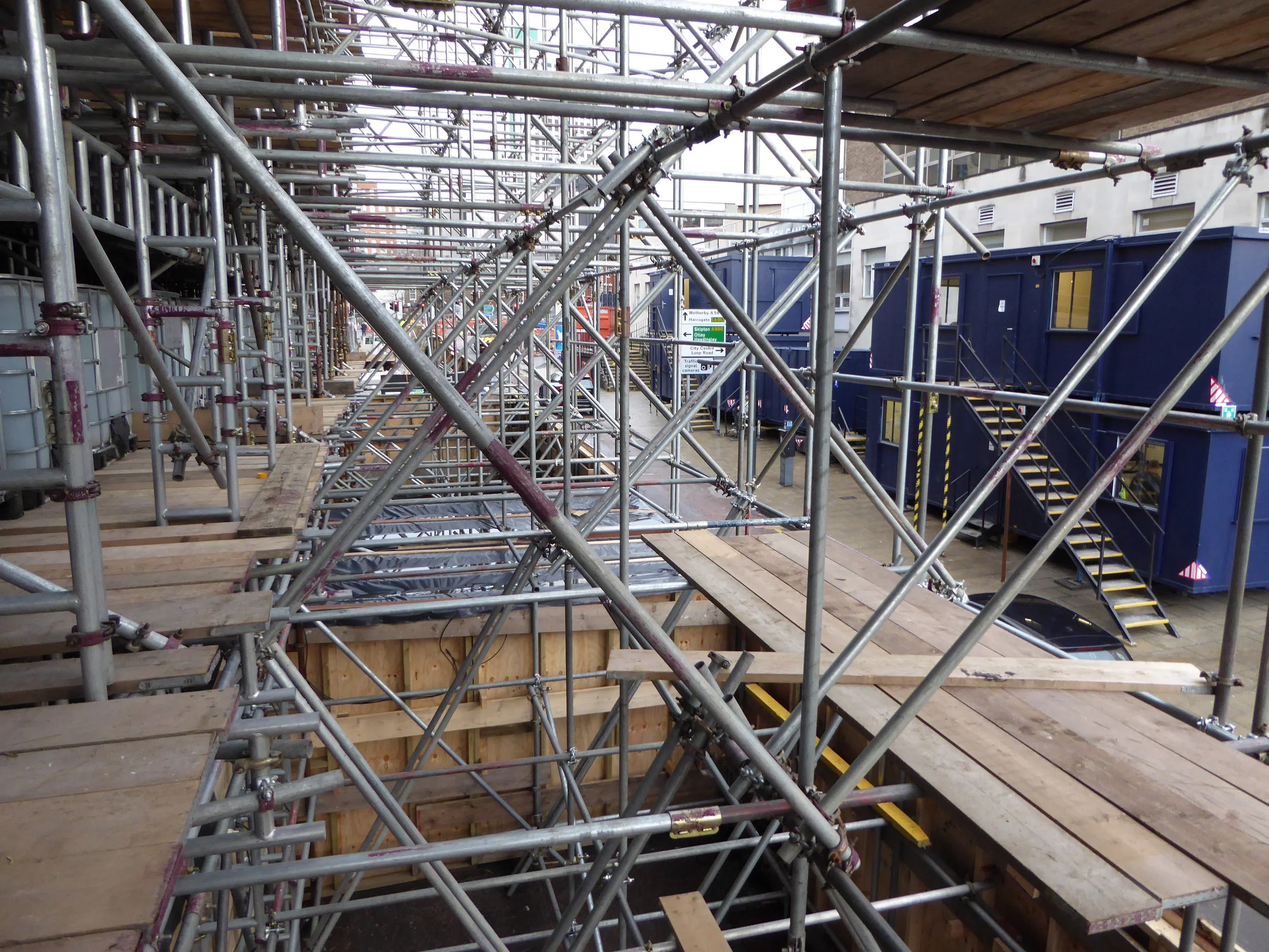 Construction site with scaffolding and blue portable structures on a city street.
