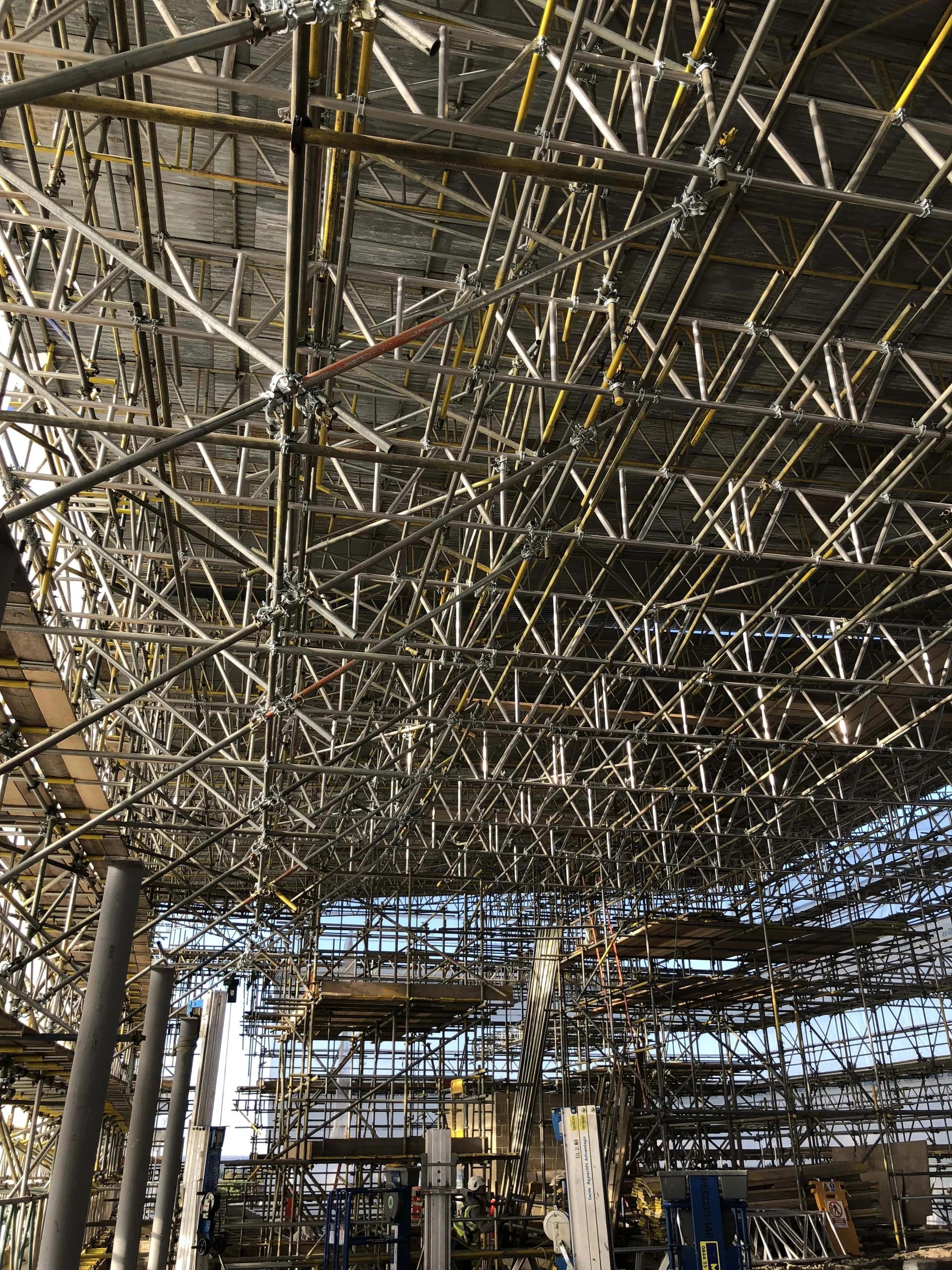 Construction site with extensive scaffolding and metal framework inside a building under construction.