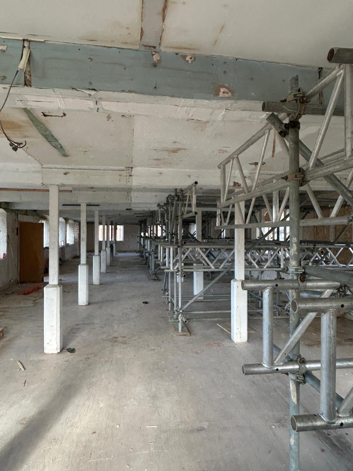 Construction site with scaffolding and support beams in an unfinished building interior.