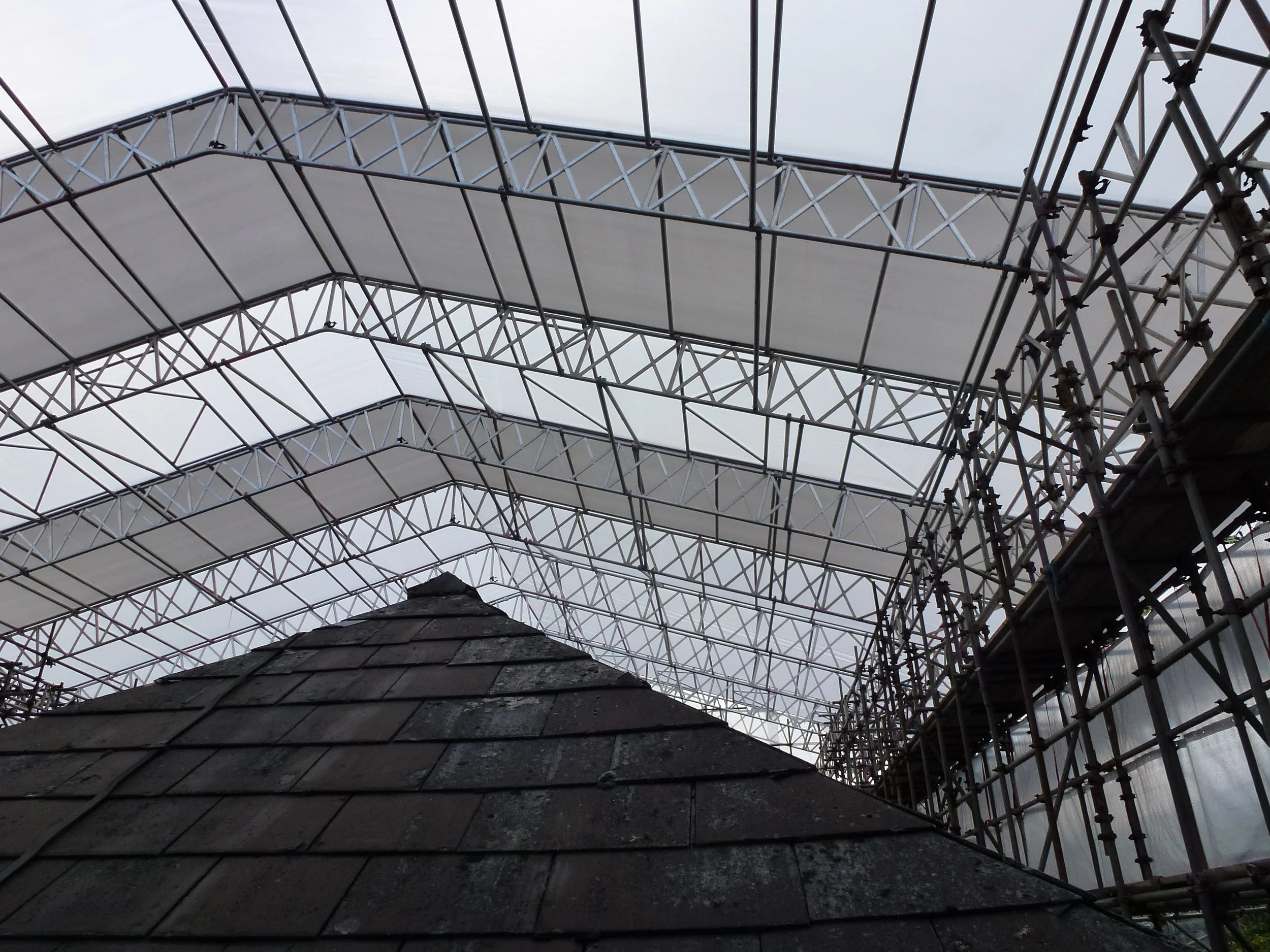 Roof of a building with scaffolding and a large white tarp or fabric covering it.