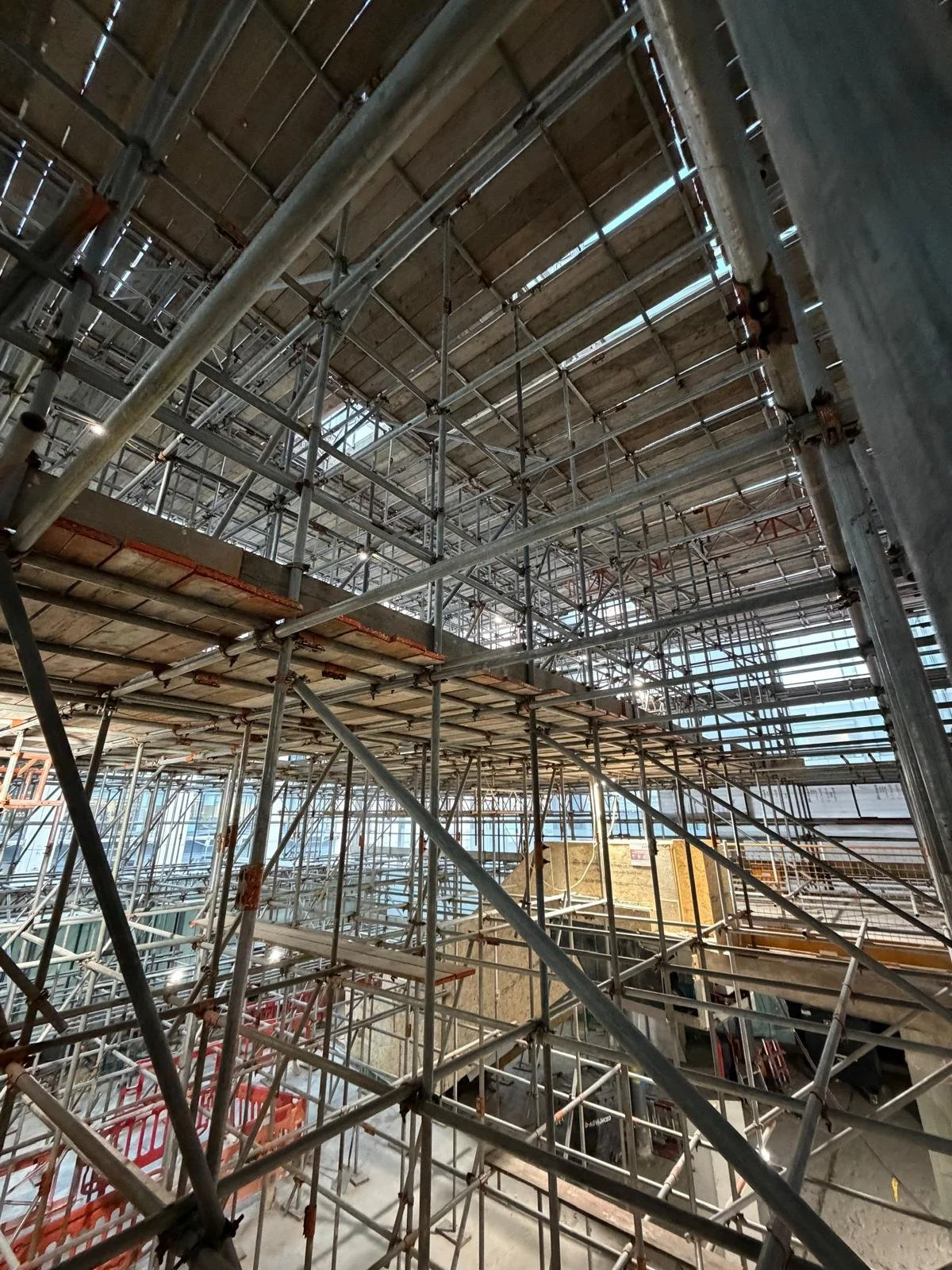 Inside view of a building under construction with multiple levels of scaffolding and wooden work platforms.