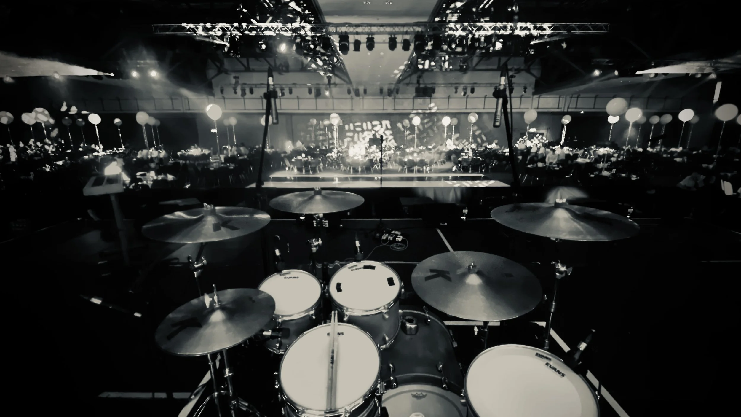 Concert hall stage with musical instruments, stage lighting, and empty seats in the background.