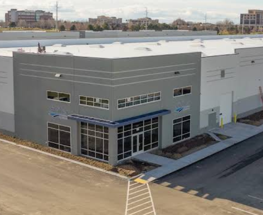 Commercial warehouse building with large glass doors and windows, situated in an industrial area.