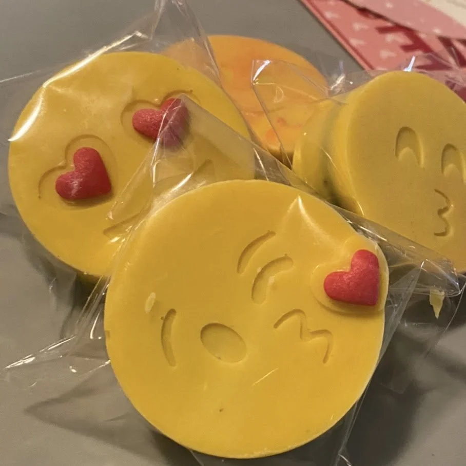 Yellow oreos with smiley face and heart-shaped pink decorations, wrapped in clear plastic.