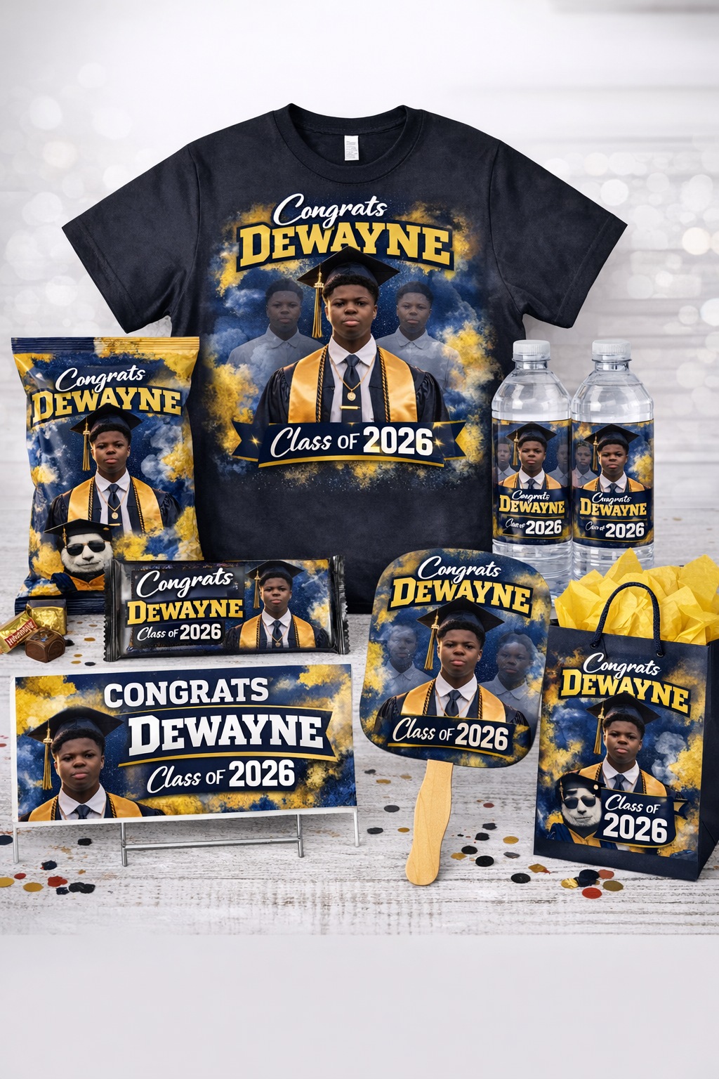 Graduation-themed party favors for Dewayne's graduation, including a t-shirt, cookie, and water bottles, all featuring Dewayne in a cap and gown with "Congrats Dewayne Class of 2026" branding.