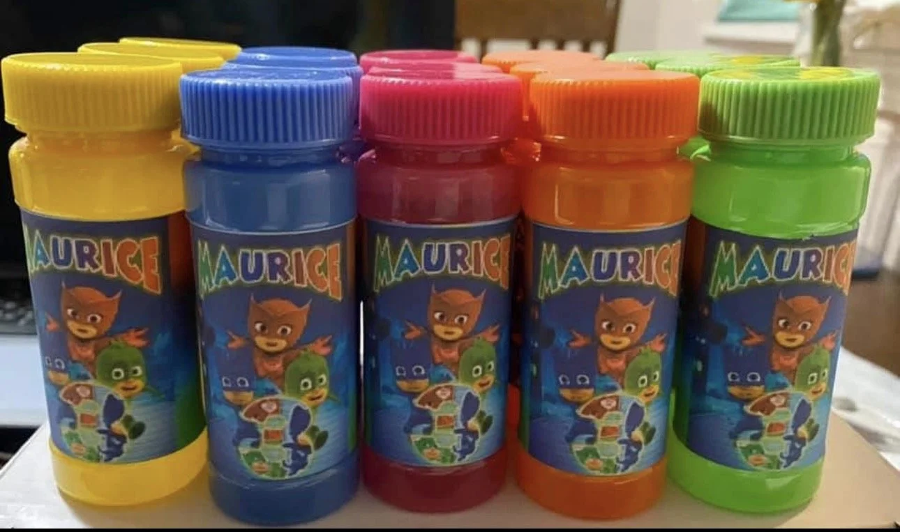 Colorful bottles of children's bubble solution with cartoon characters on the labels, arranged in rows with yellow, blue, red, orange, and green caps.