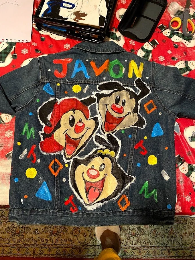 Decorated denim jacket with painted characters from Sesame Street, including Ernie, Bert, and Julie, and colorful letters spelling "JAVON" on the back.