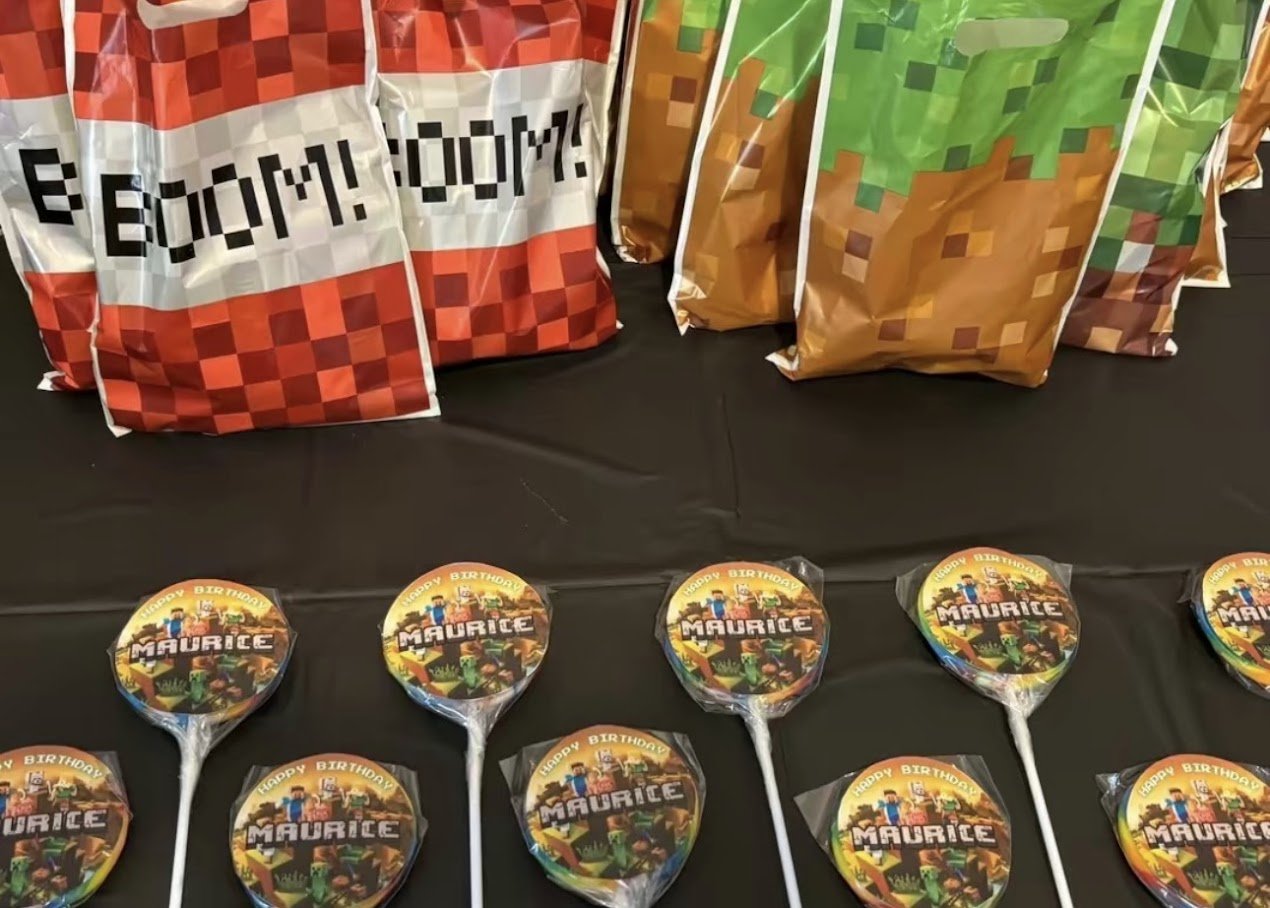 Minecraft-themed party bags and lollipops on a black table for a birthday celebration.