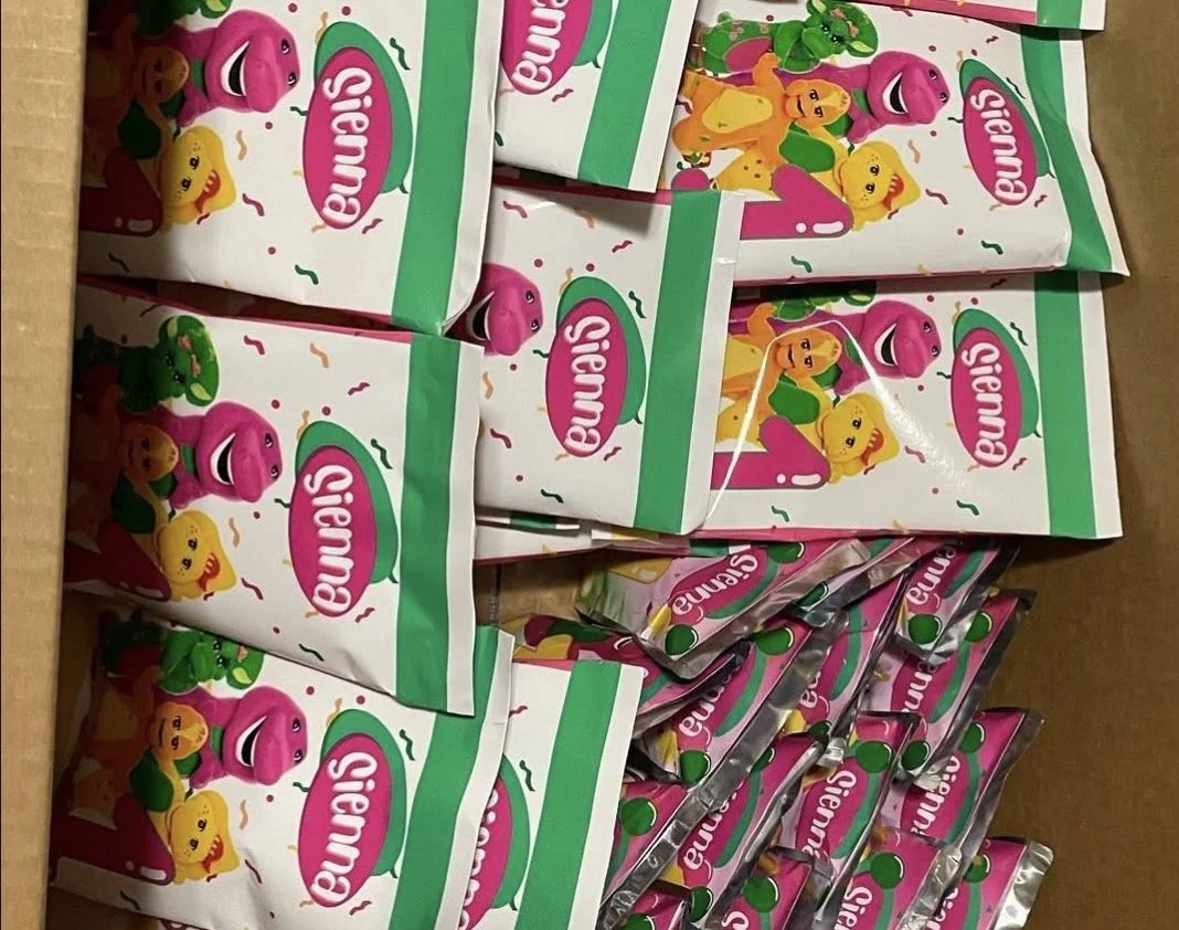 Multiple packages of Sienu's candy with pink, yellow, and green characters on colorful packaging.