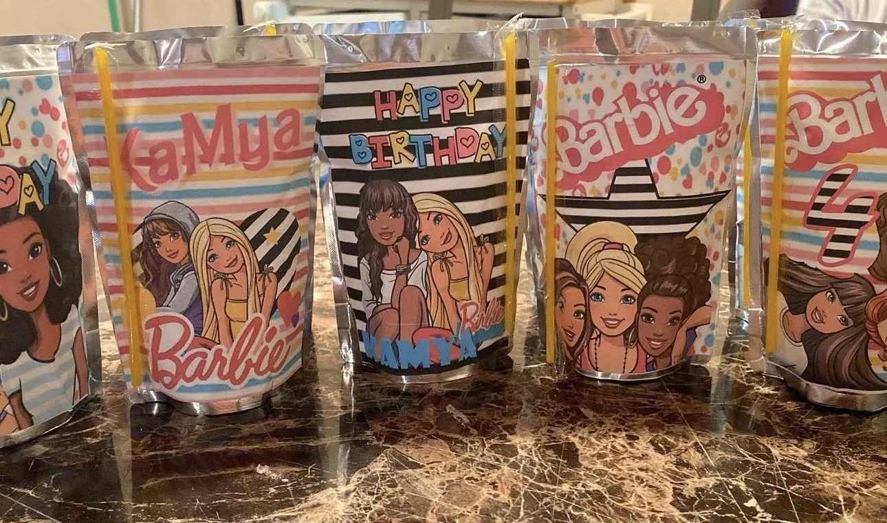 Row of customizable Barbie-themed juice boxes with illustrated cartoon girls and colorful striped backgrounds, some with personalized names and messages for birthdays.
