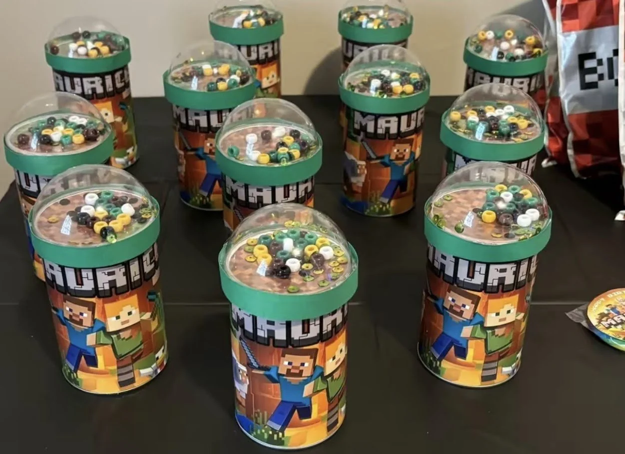 Multiple Minecraft-themed containers with colorful beads inside on a table, likely for a birthday or party.