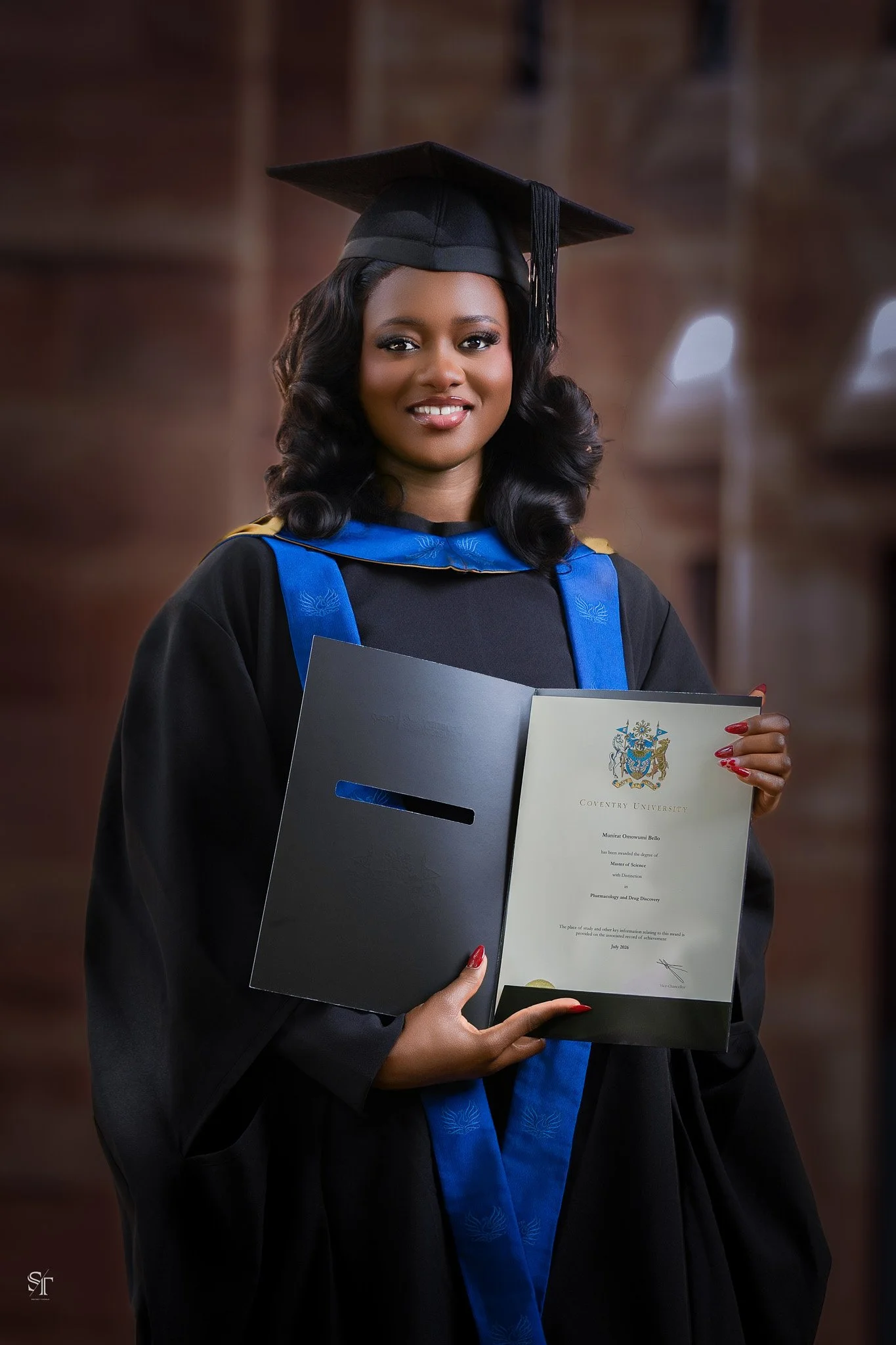 Young woman in graduation cap and gown holding diploma at graduation ceremony.