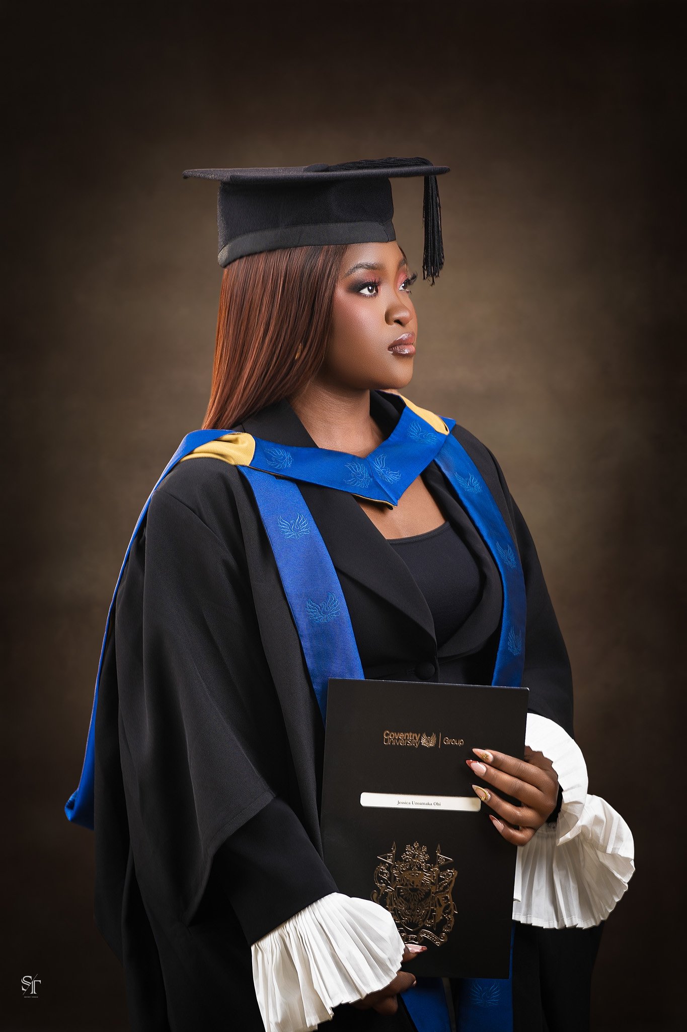 Woman in academic regalia with brown hair, wearing a black mortarboard cap, and holding a diploma in front of a brown gradient background.