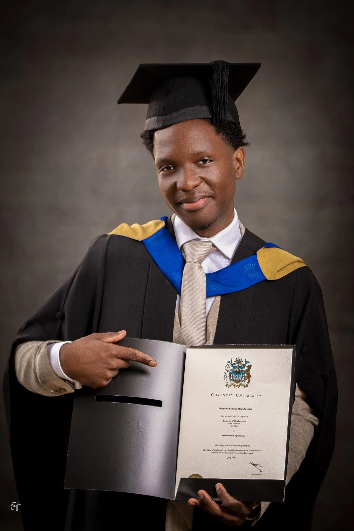 Young man in graduation gown and cap holding a certificate from Coventry University.