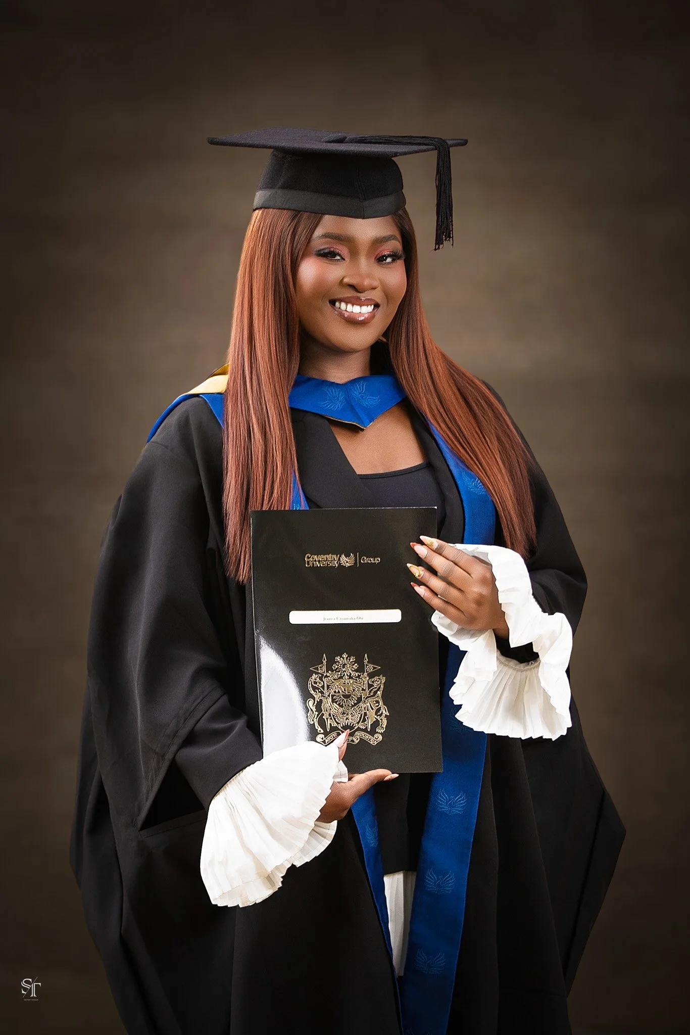 A young woman in a graduation cap and gown holding a diploma and smiling.