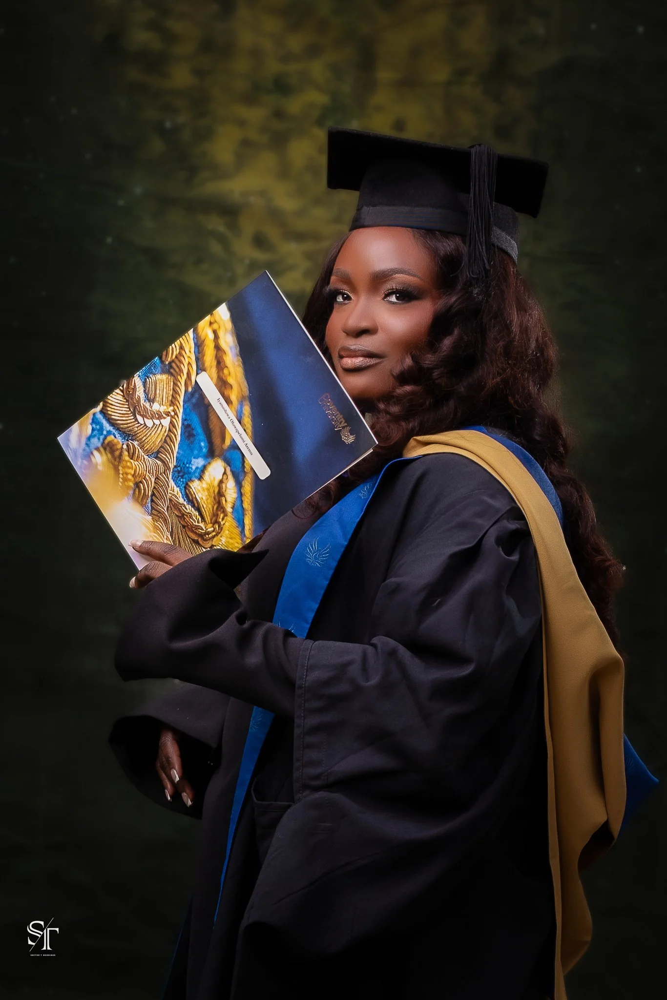 A woman in graduation attire, including a black cap and gown, holding a diploma in front of a blurred green background.
