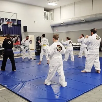Martial arts students practicing in a dojo with an instructor leading the session.