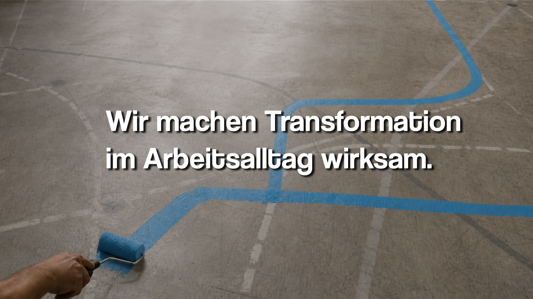 Jemand malt eine blaue Linie auf einer Sporthalle mit einem Farbroller, im Vordergrund die Hand der Person, die den Farbroller hält, und im Hintergrund der Boden mit mehreren gestrichelten Linien. Text in der Mitte: 'Wir machen Transformation im Arbeitsalltag wirksam.'