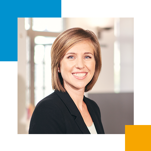 Ein Lächeln einer jungen Frau mit braunen Haaren, die in einem Büro arbeitet.