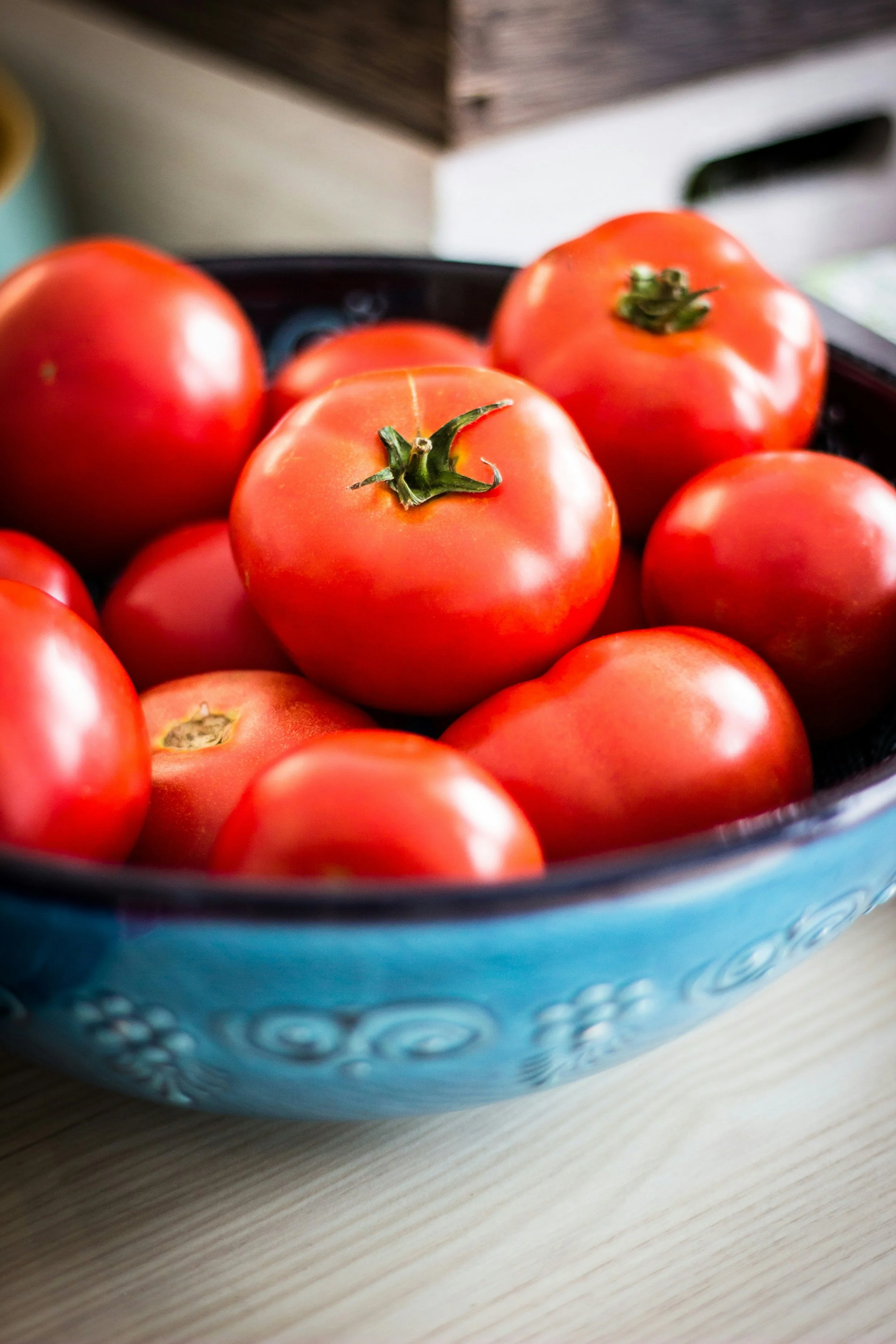 Close-up of a bowl with red tomatoes on a wooden surface.