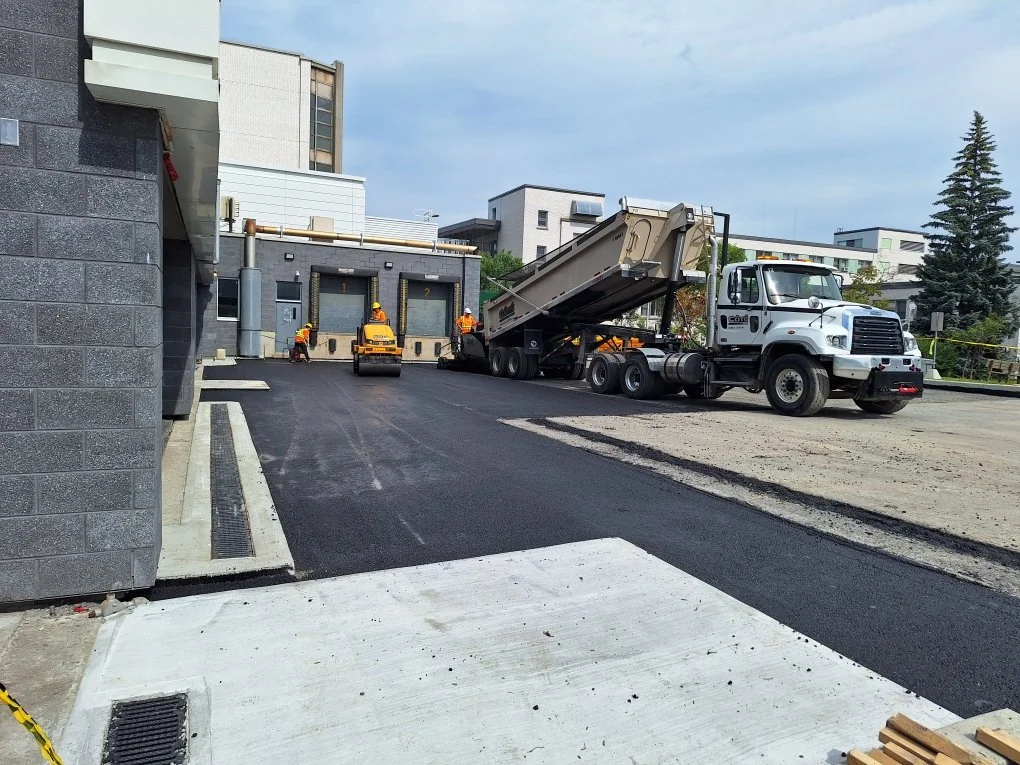 Travaux de pavement avec une équipe d'ouvriers et un camion-malaxeur sur un site résidentiel.