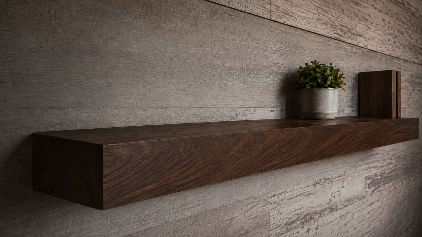 Dark walnut wood floating shelf with potted plant and book on a textured wall.
