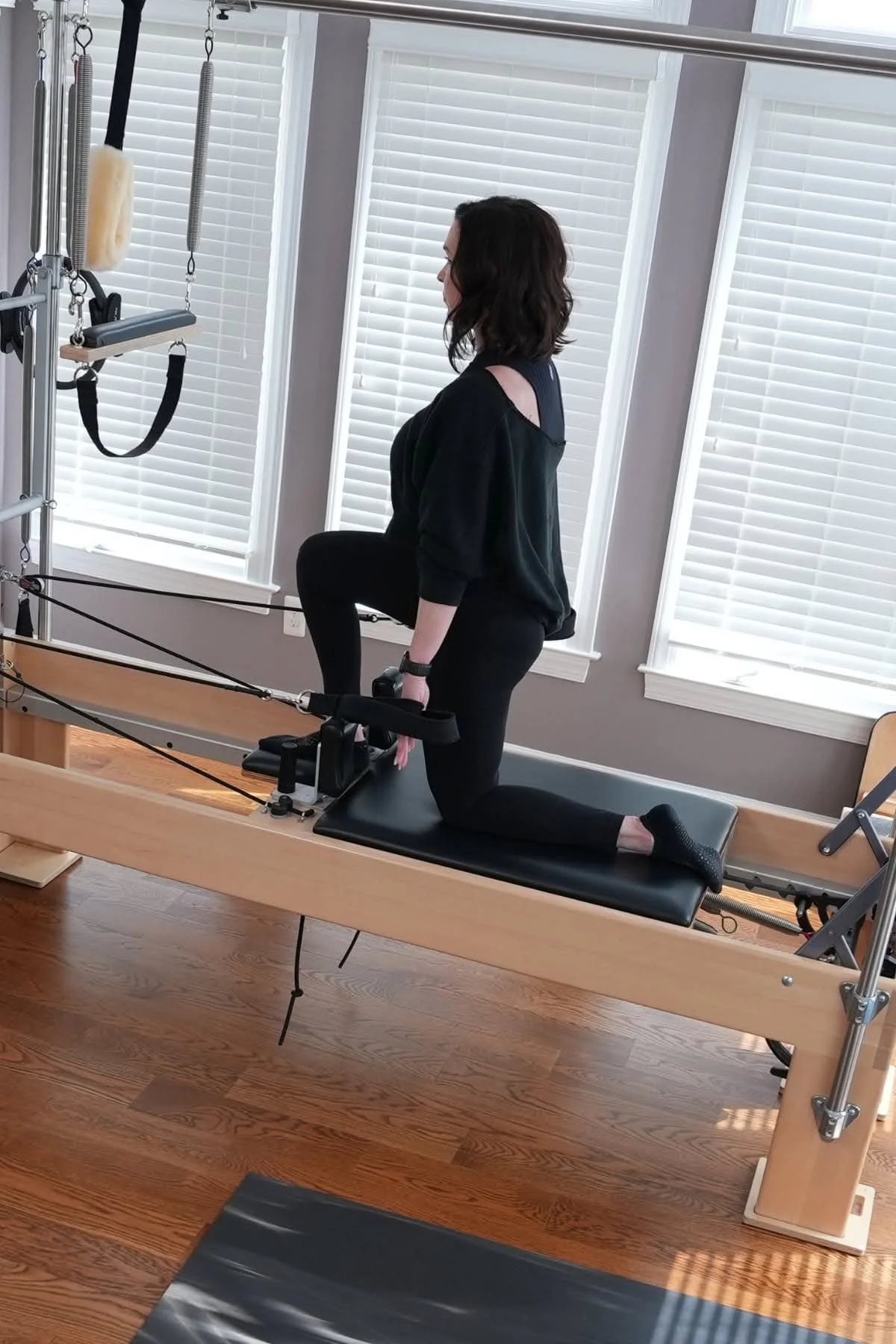 women with dark hair on a pilates reformer