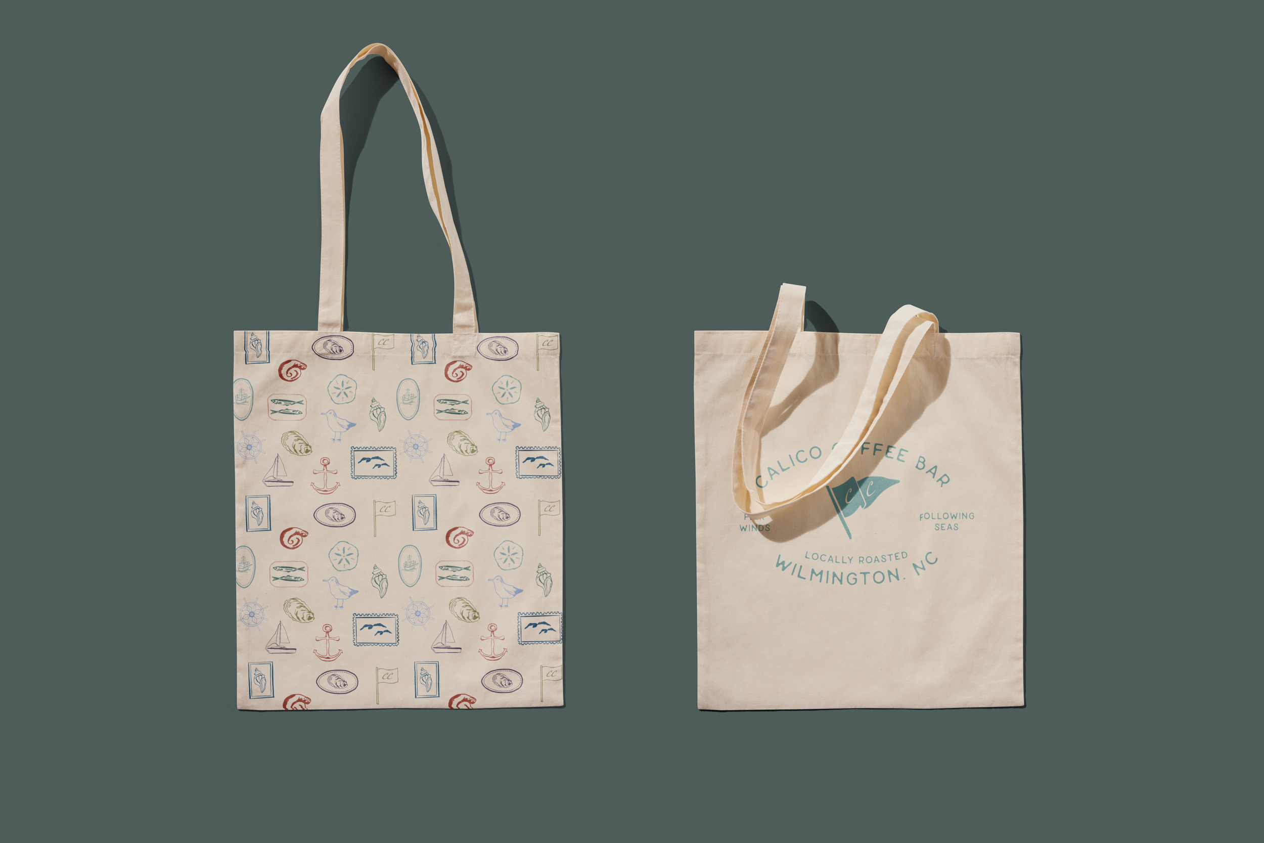 Two reusable fabric tote bags, one with colorful seaside-themed illustrations and the other with a 'Calico Coffee Bar Wilmington NC' logo, placed on a solid green background.