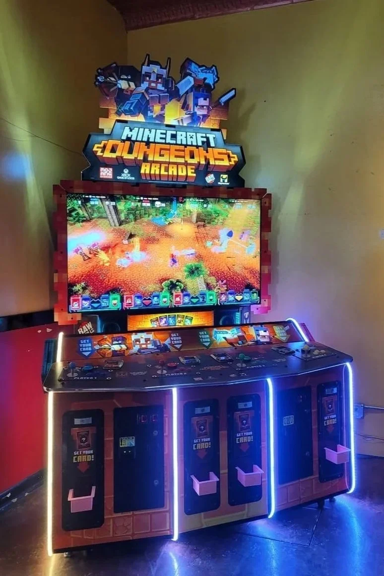 Minecraft-themed arcade game machine with a screen displaying a Minecraft landscape, surrounded by pixel art graphics and controls, set in an illuminated gaming area.