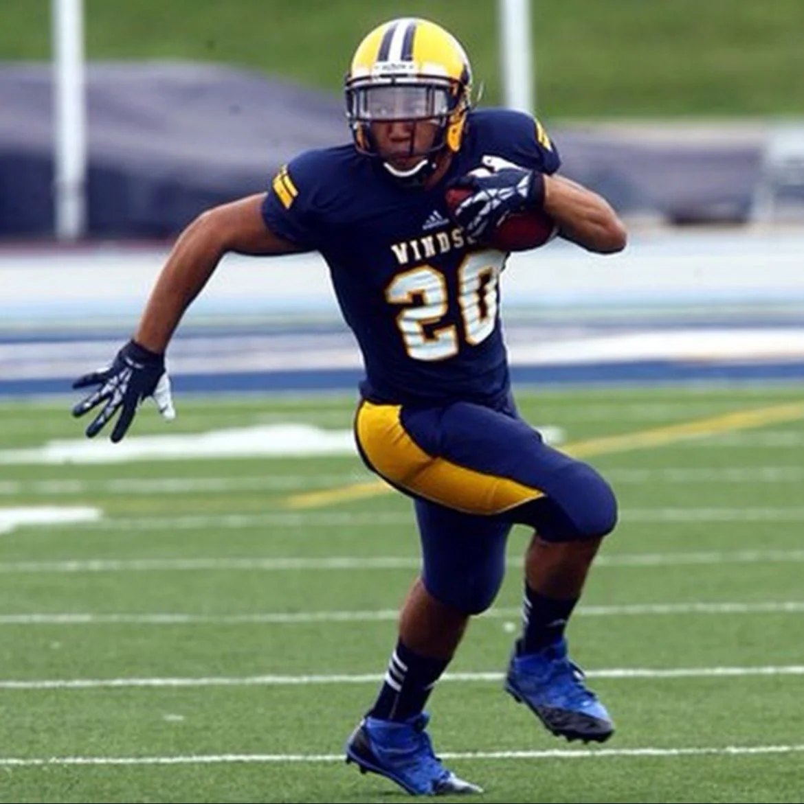 An American football player wearing a blue and yellow uniform, number 20, running with a football on a field.