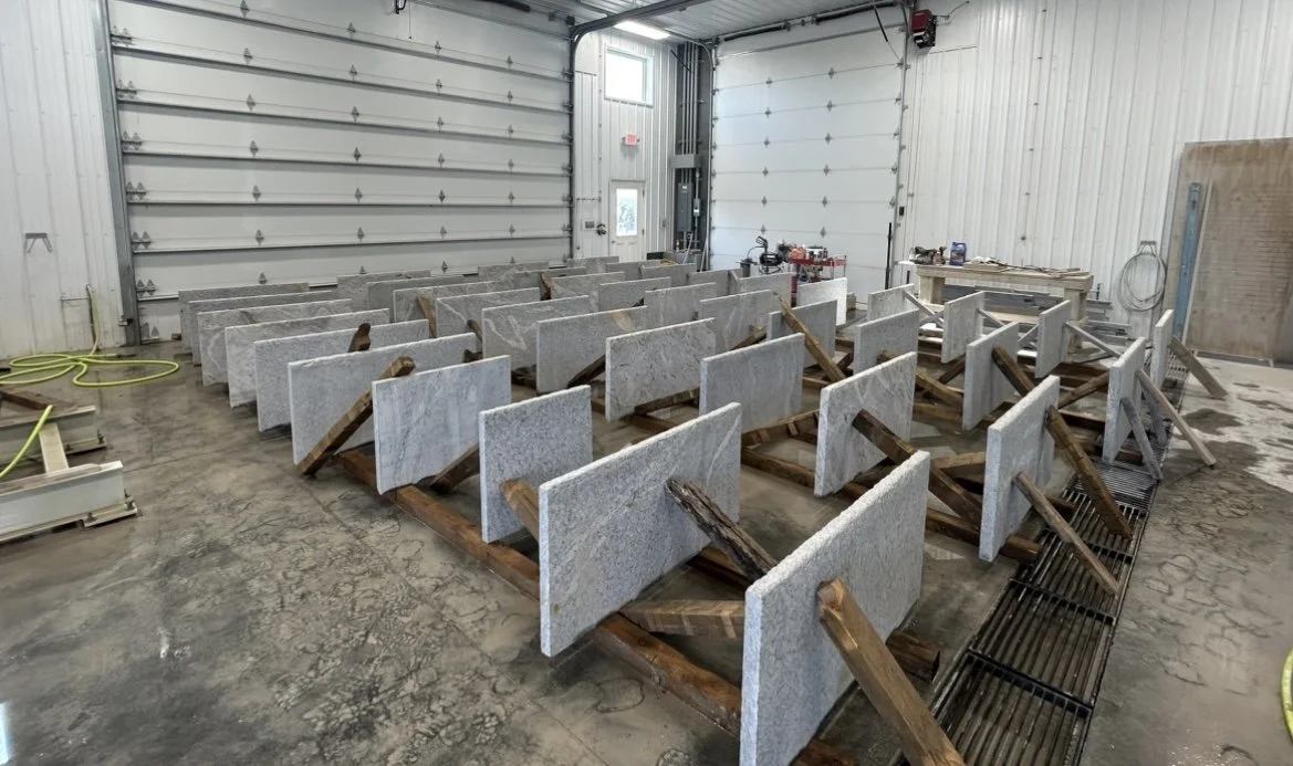 Multiple stone countertops with wooden supports stored inside a garage or workshop.