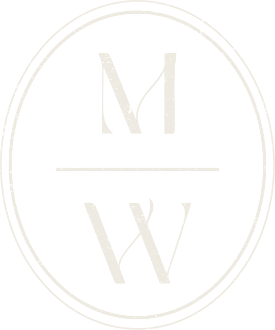 A logo with an oval shape containing the letters M, V, and W arranged vertically.