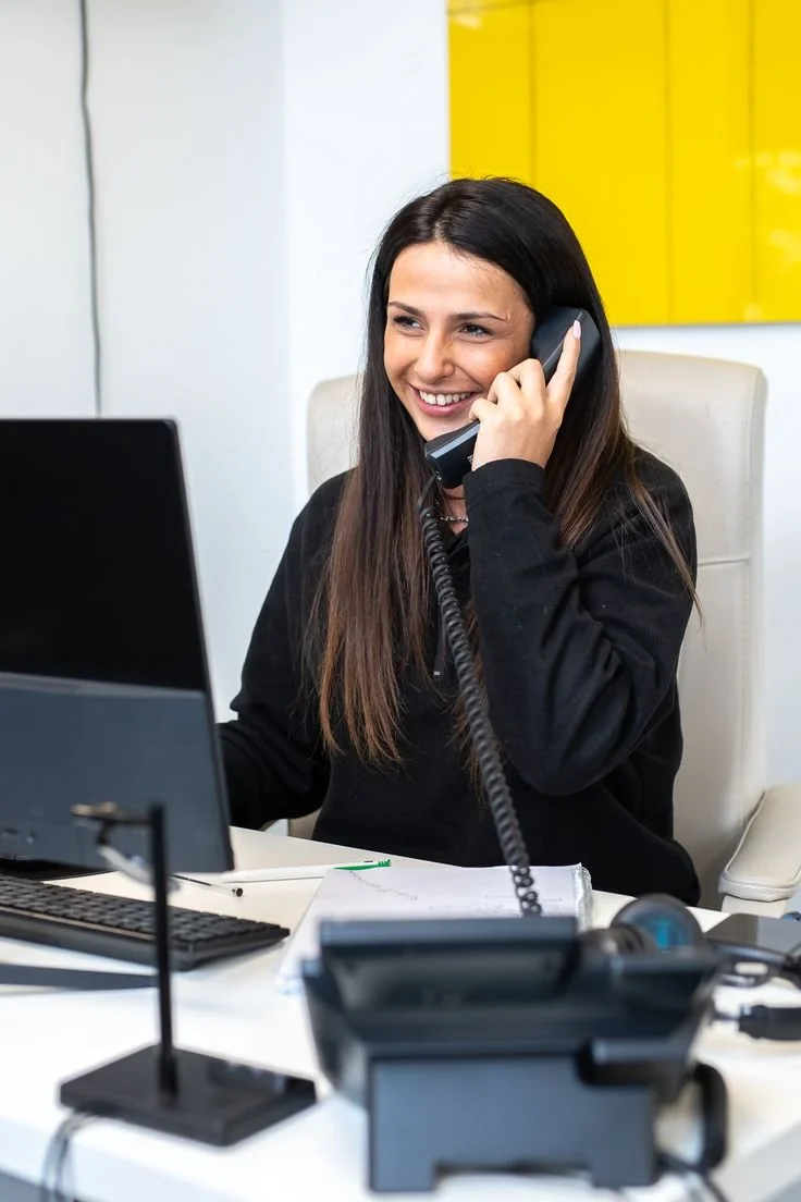 Woman smiling and talking on the phone at her desk in an office.