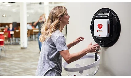 A woman using an automated external defibrillator (AED) in an airport or public space.