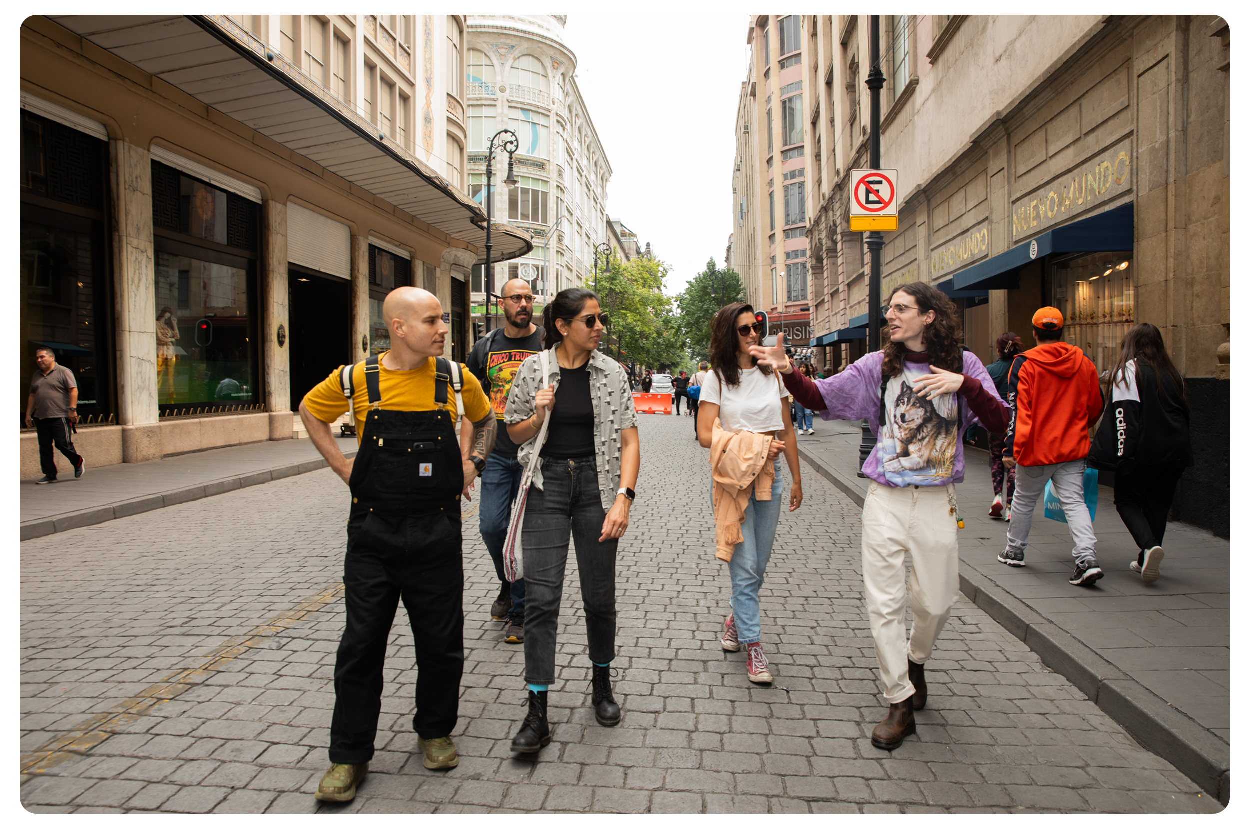 A group of diverse people walking and talking on a city street during the day.