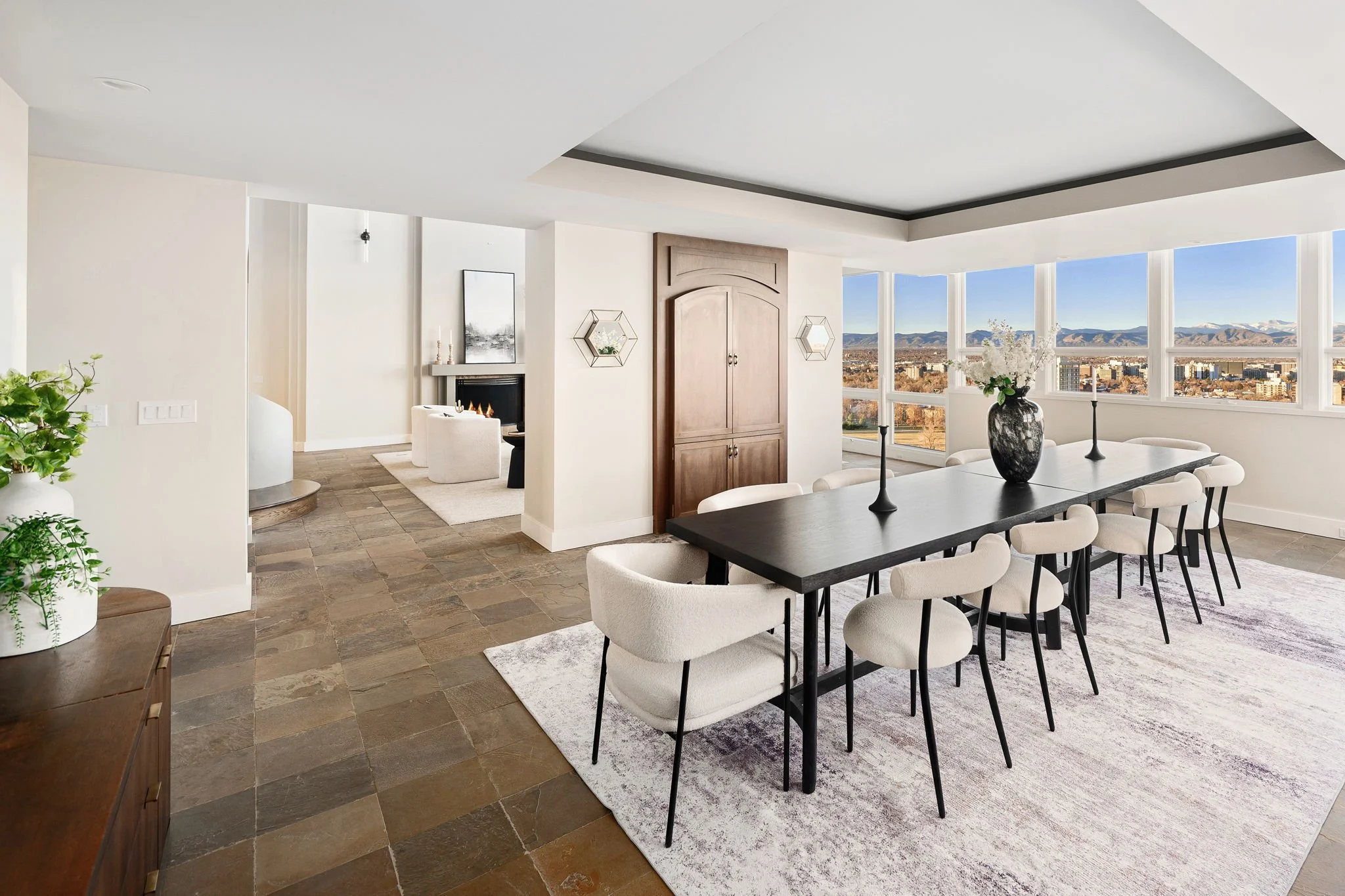 Modern dining room with black table, white chairs, and large windows showing mountain view
